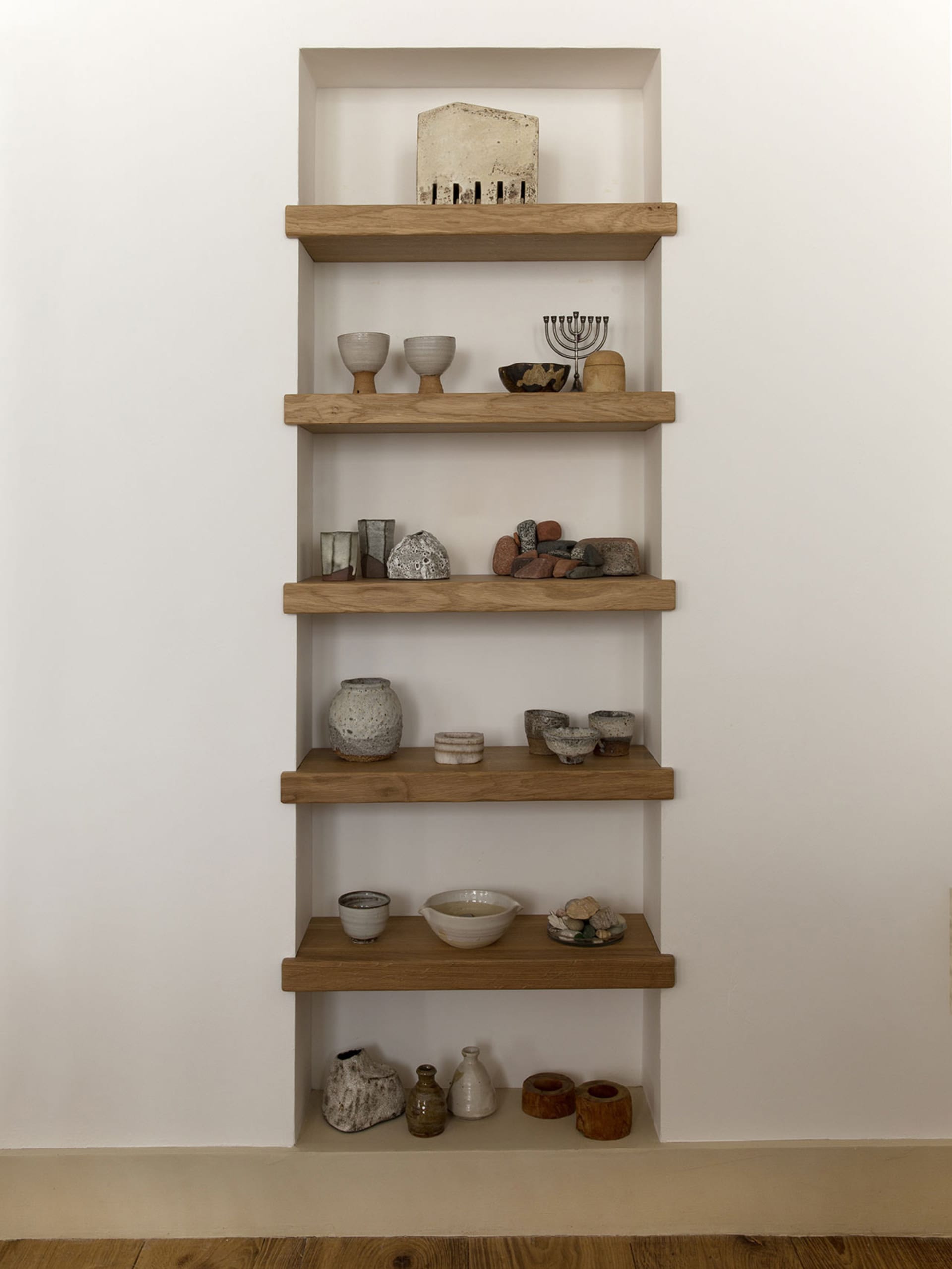 A collection of various ceramics and rocks displayed on wooden shelves.