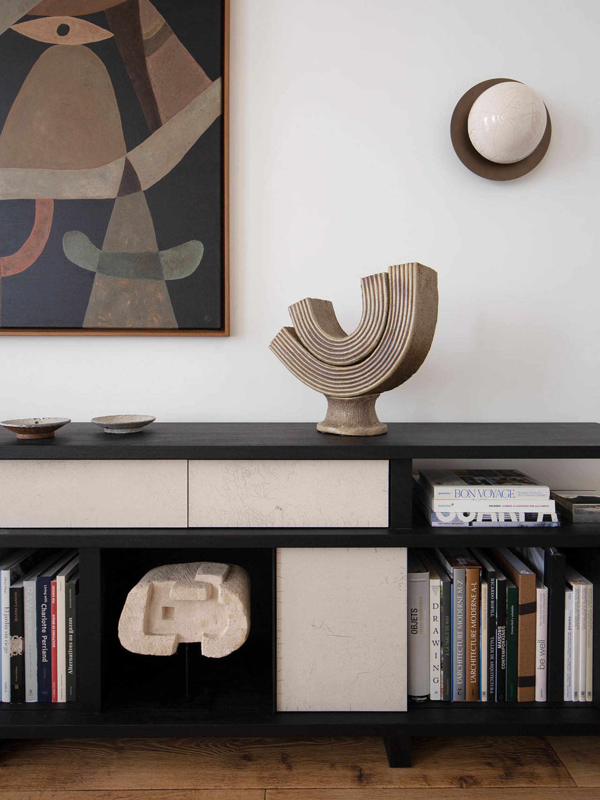 A modern interior featuring a black sideboard with ceramic sculptures and books.