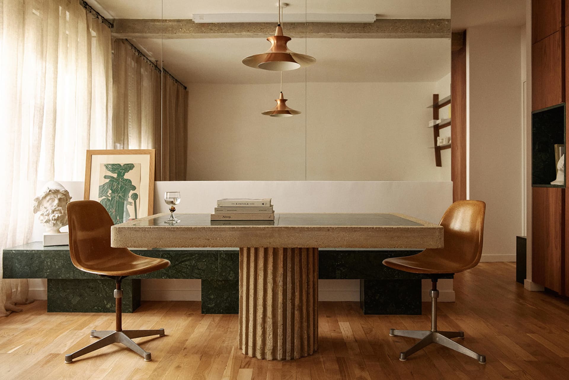 A minimalist living room with a concrete table and brown chairs.