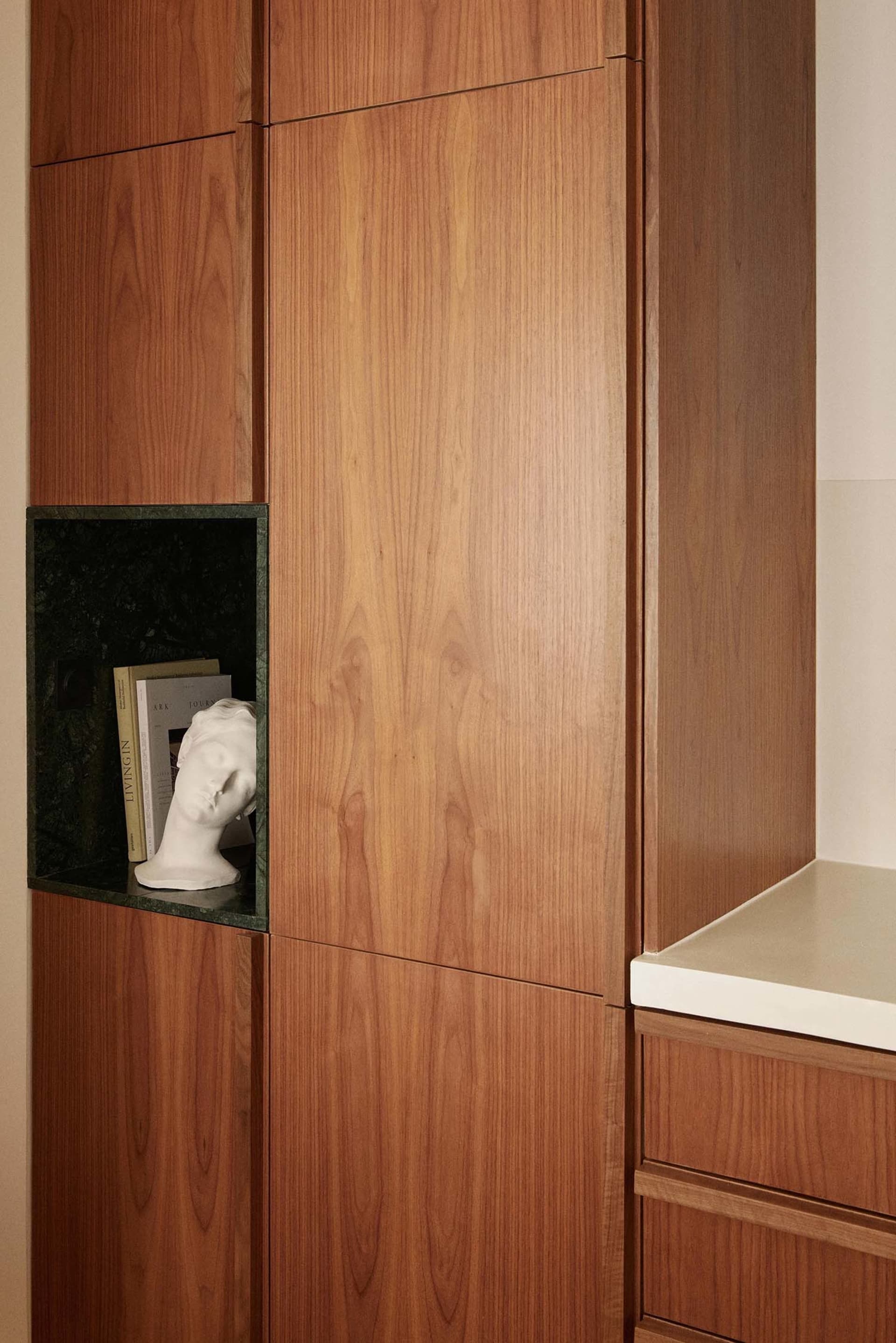 Modern wooden storage unit with a niche for books and a bust sculpture.