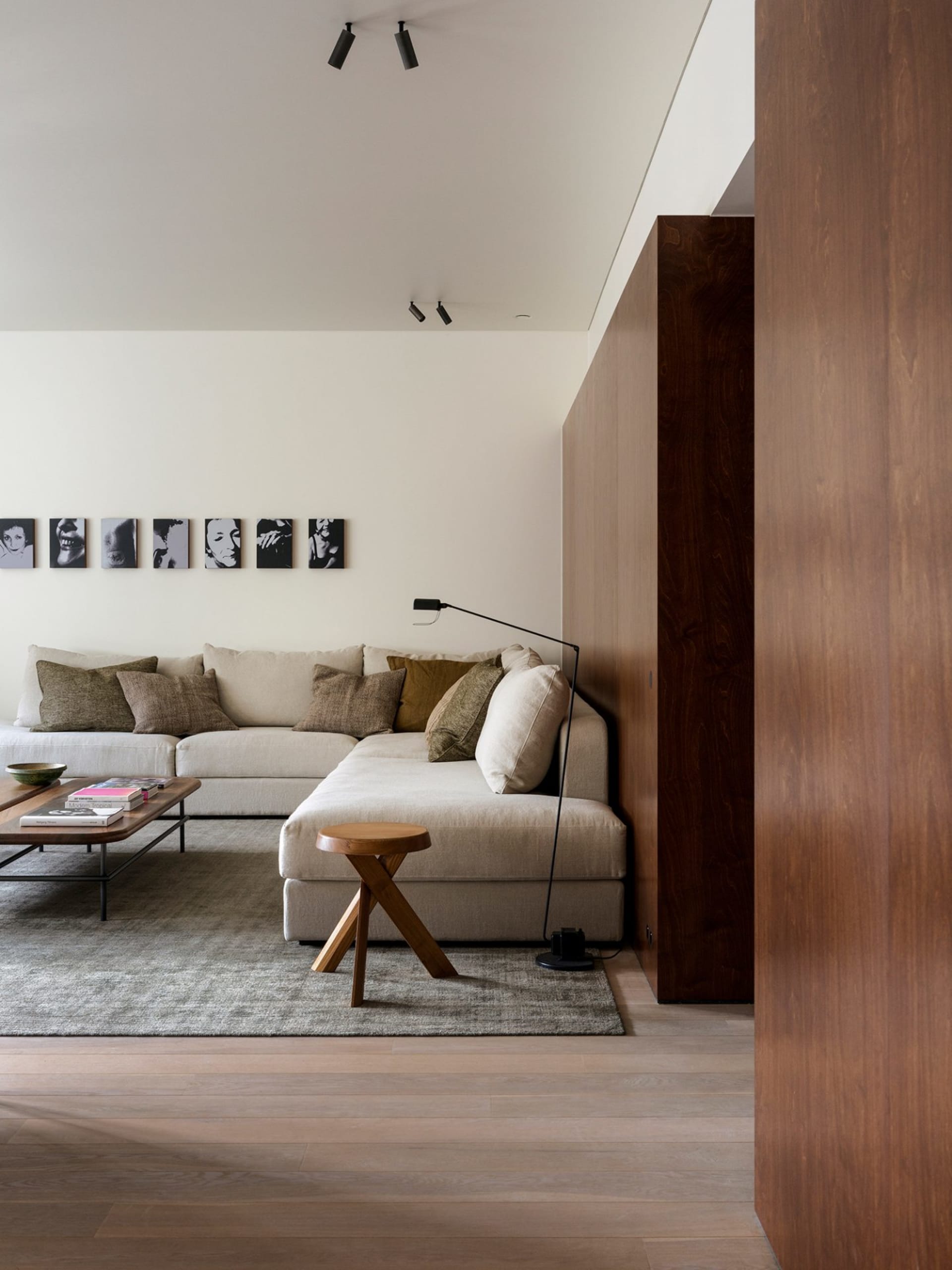 A cozy, minimalist living room with a large sectional sofa, wooden accents, and a floor lamp.