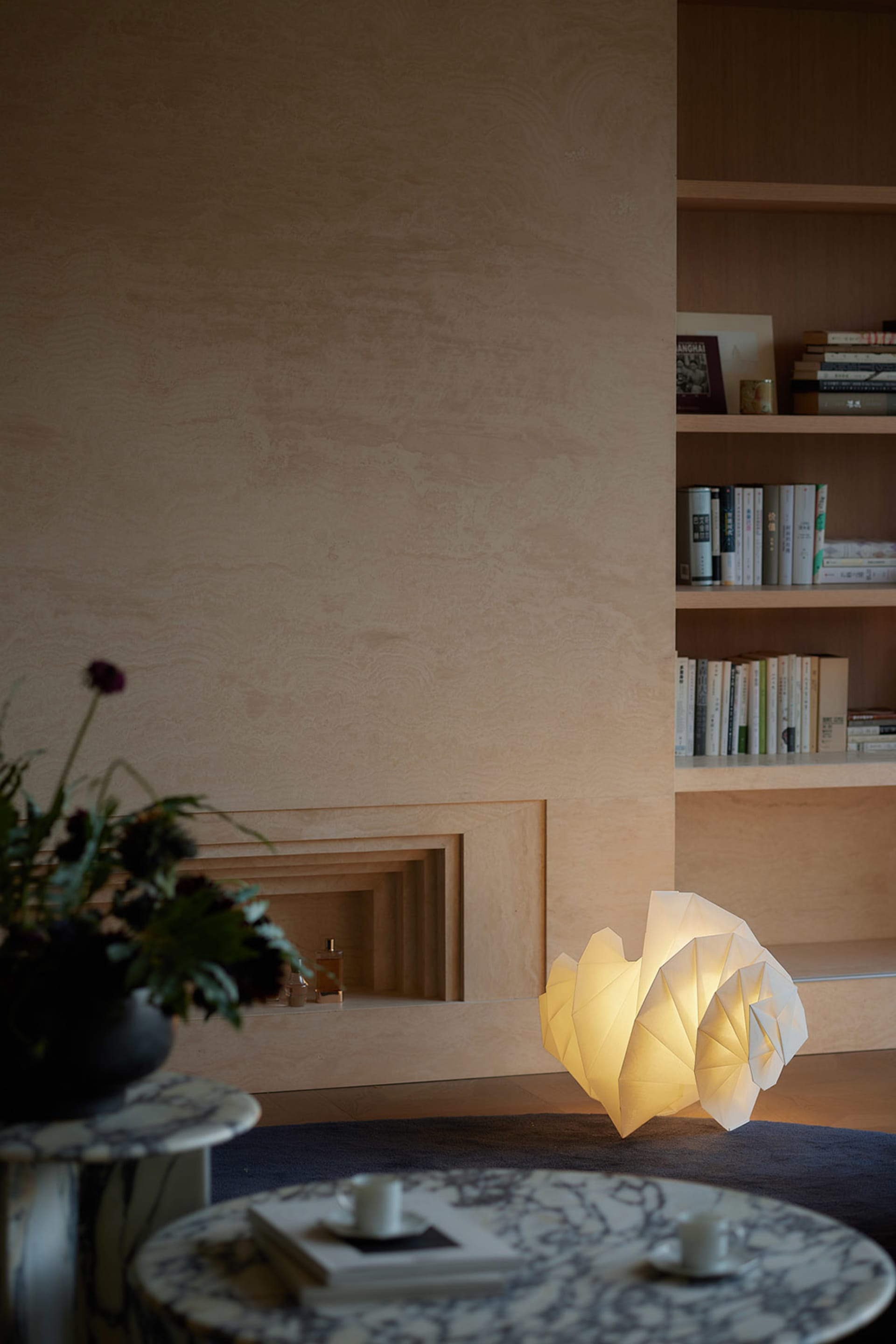 A minimalist living room featuring a uniquely designed paper table lamp emitting a warm glow.