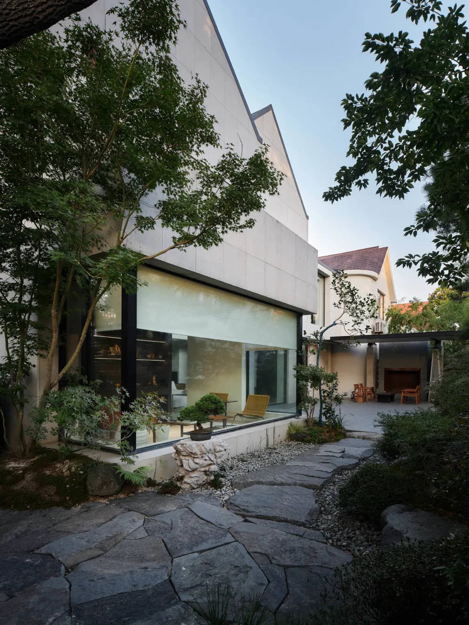 現代住宅外觀採用混凝土立面、大型玻璃窗,以及通往入口的石板步道。