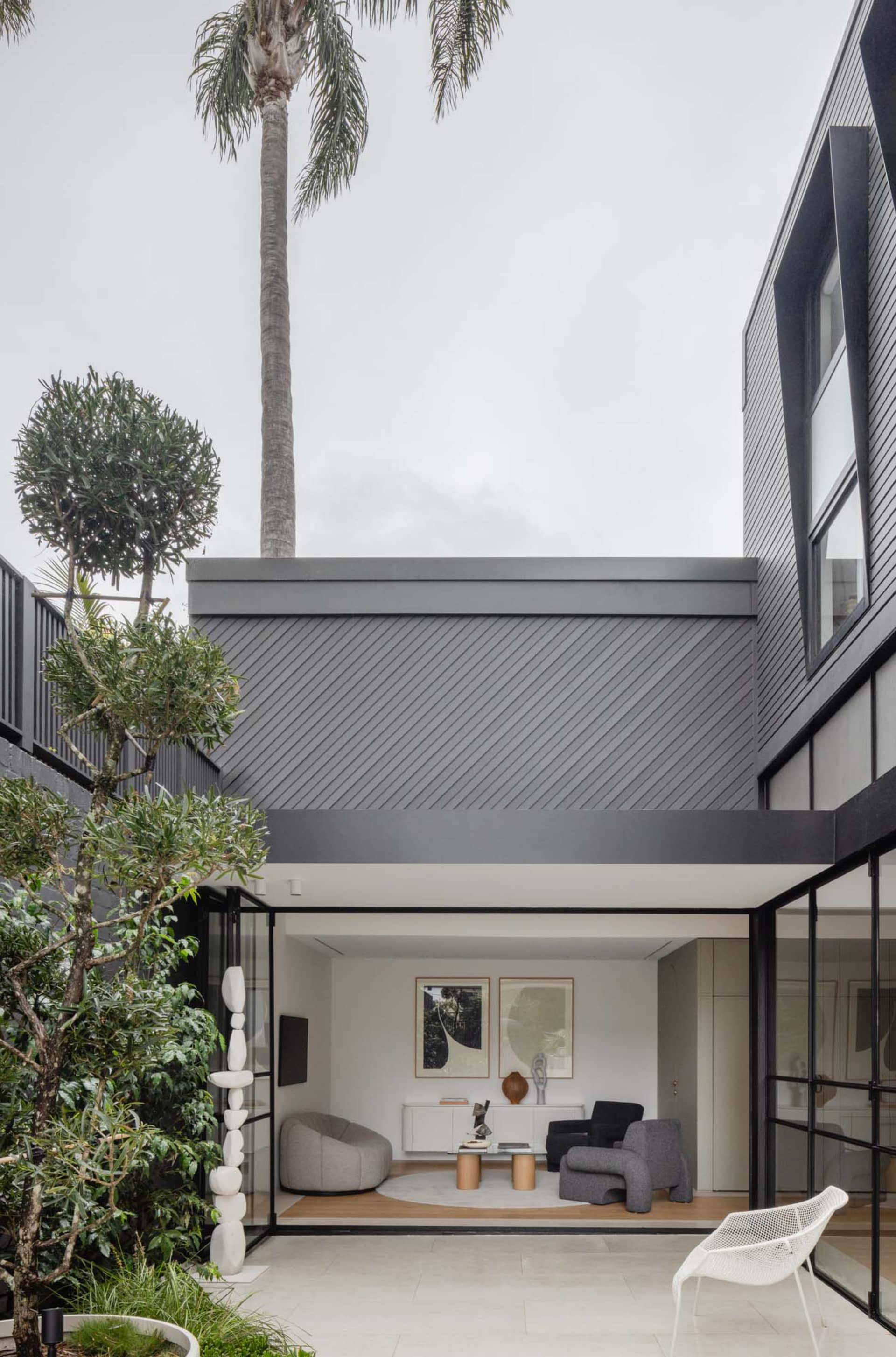 Modern, minimalist living room with concrete walls, sleek furniture, and large windows.