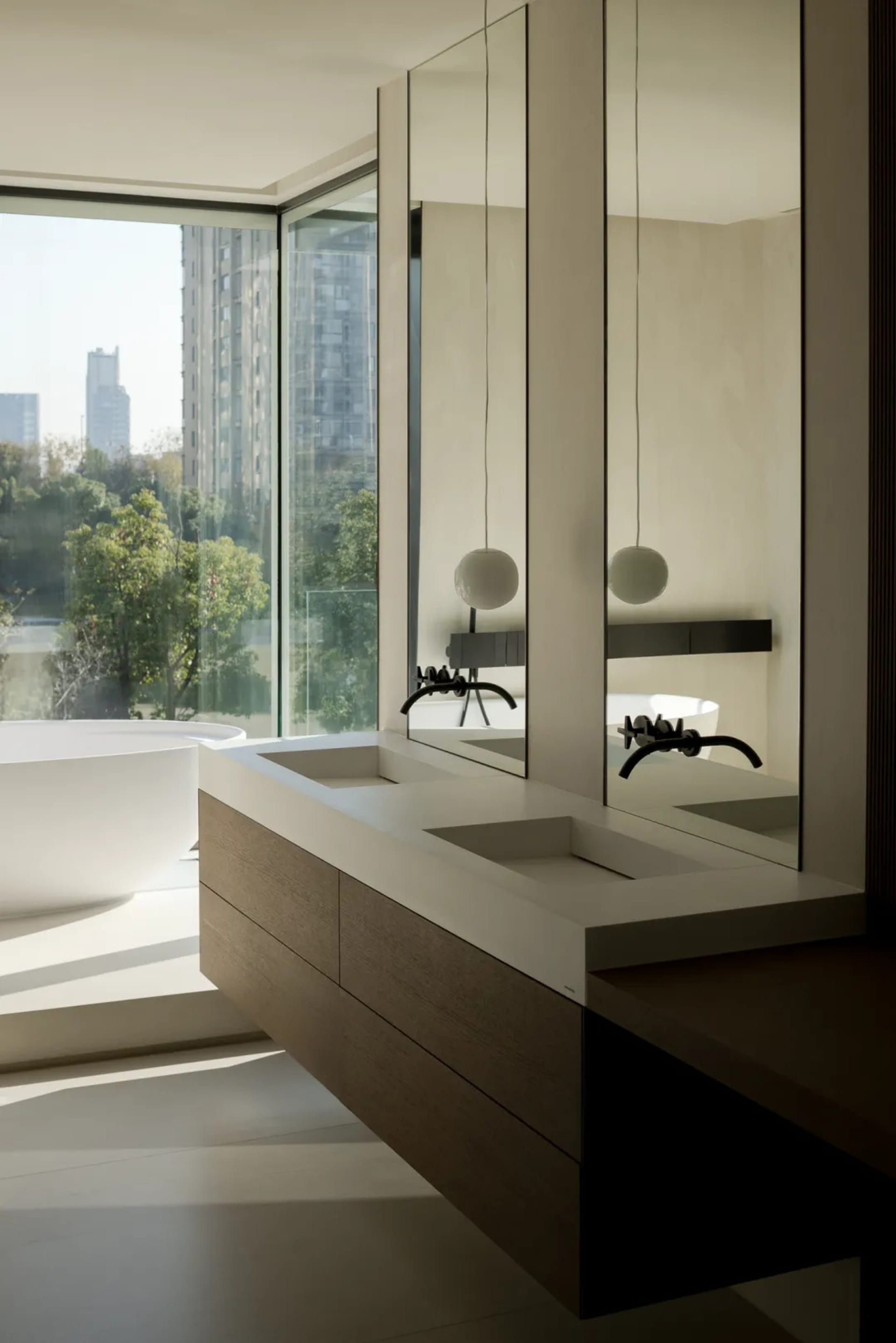 Modern minimalist bathroom featuring a white bathtub, wooden countertop with double sinks, and large glass windows overlookin