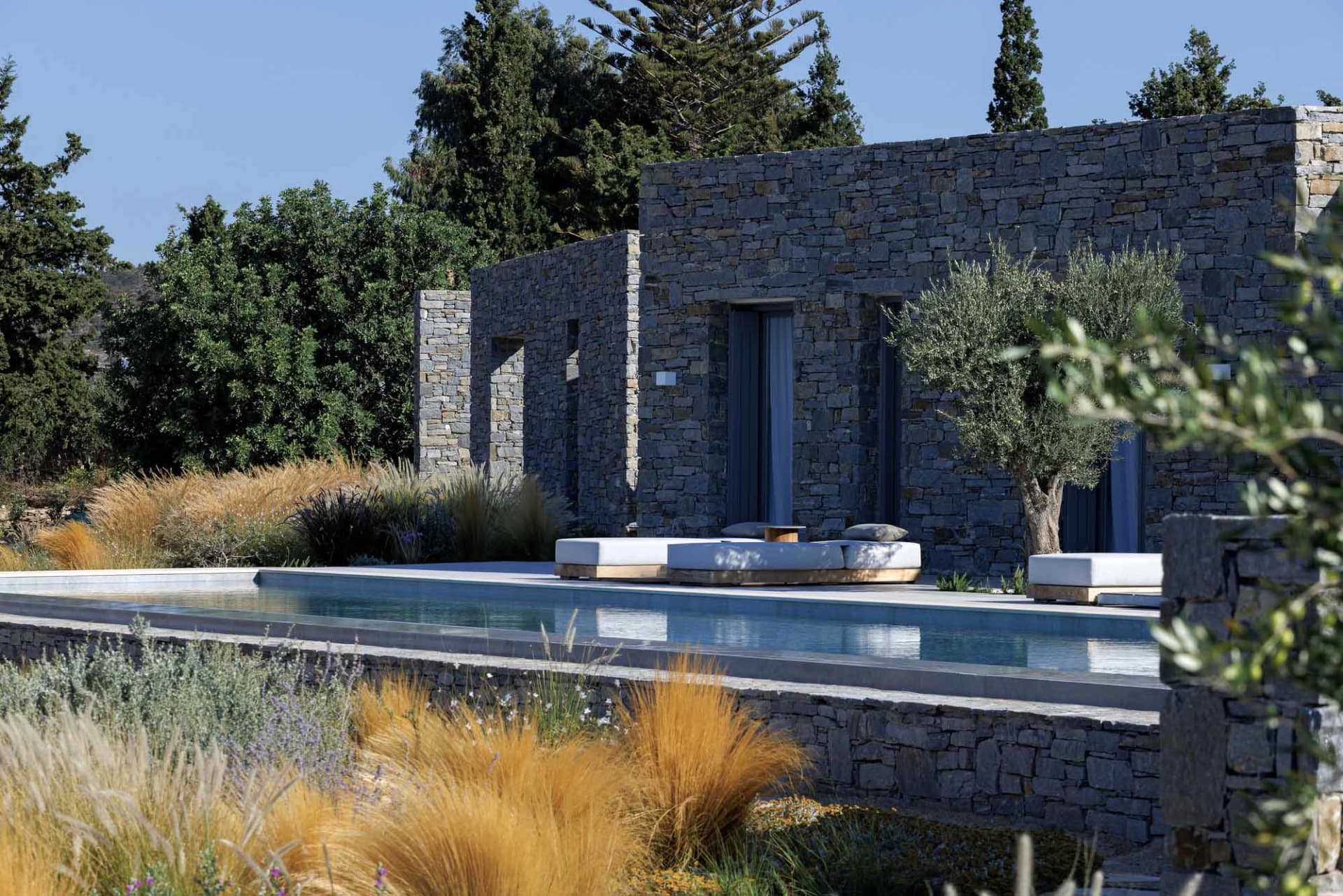 Modern outdoor living space with stone walls featuring comfortable seating and a sleek poolside design.