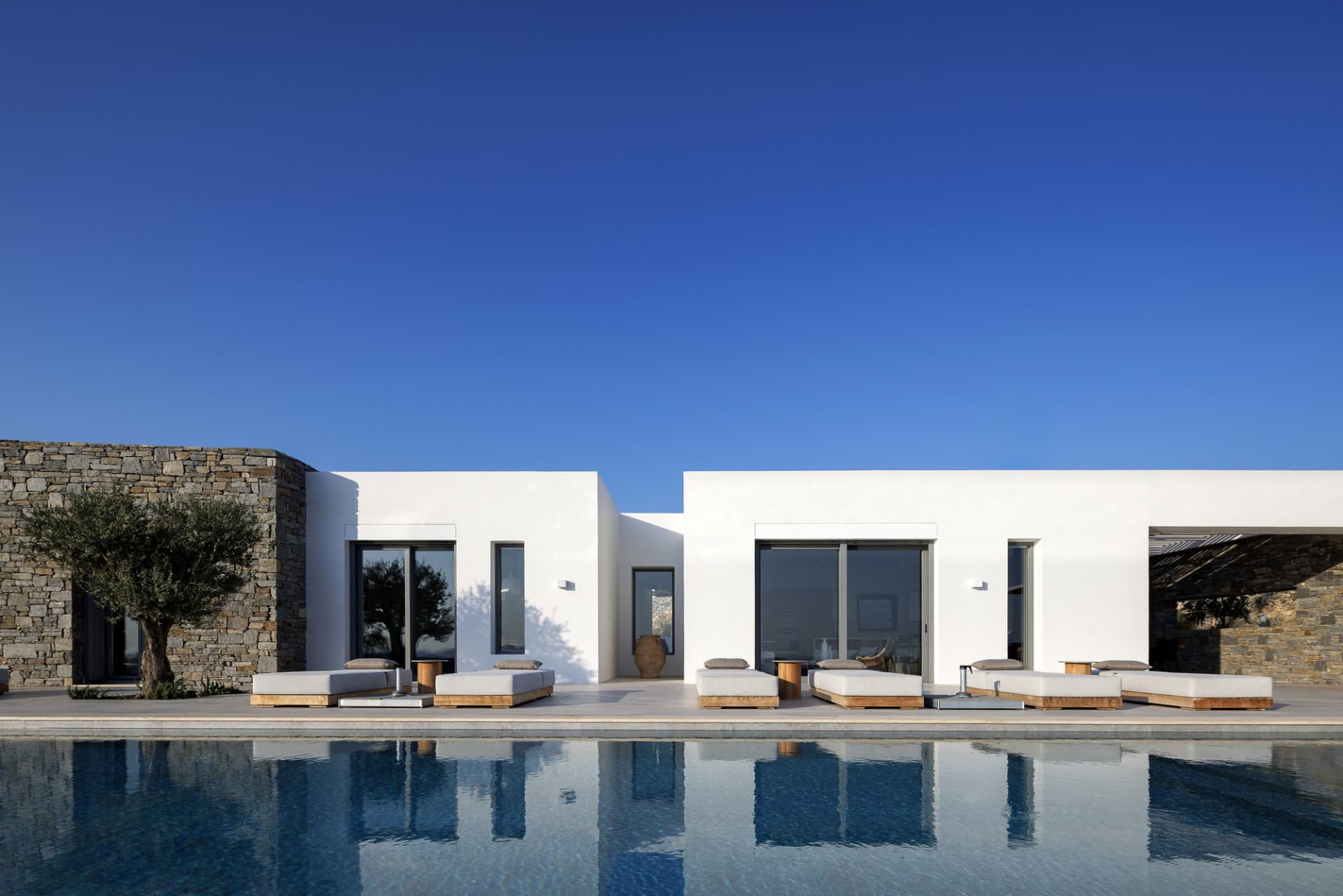 White minimalist vacation home with a pool and lounge chairs.