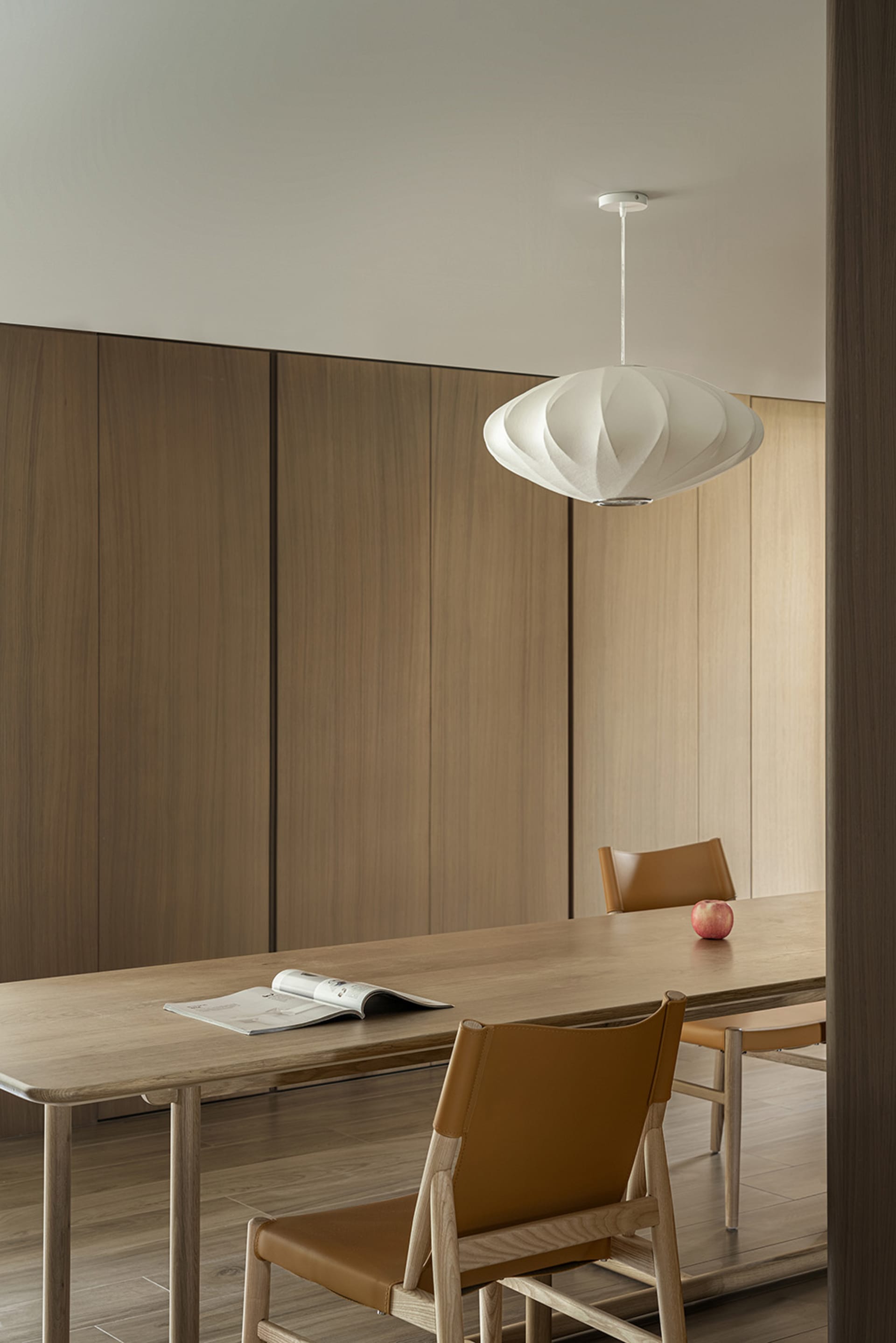 Modern dining room with wooden furnishings and a geometric pendant light.