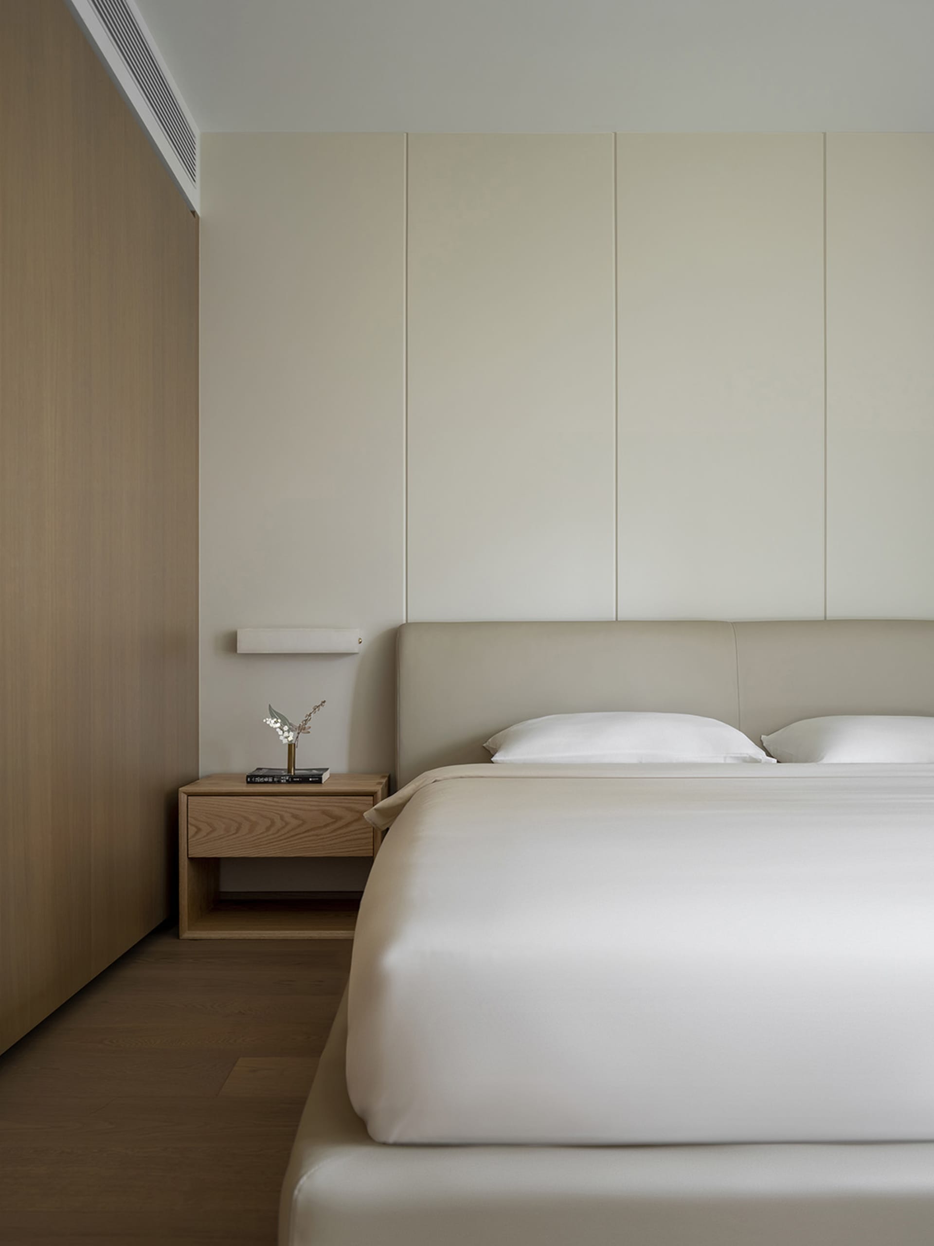A modern minimalist bedroom with neutral tones and wood accents.