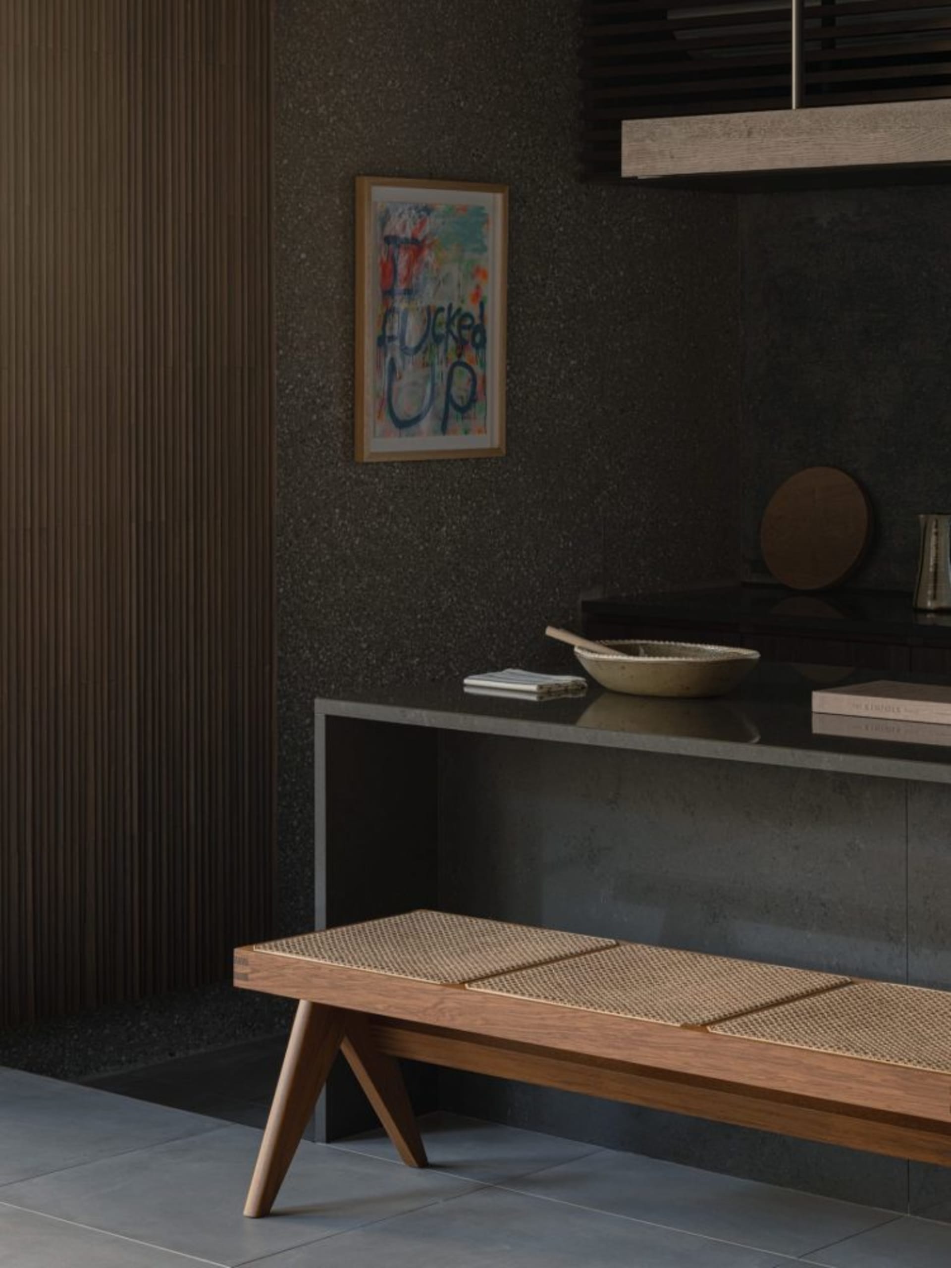 A modern entrance hall featuring a wooden bench with a woven seat, a concrete wall with a colorful abstract painting, and a c