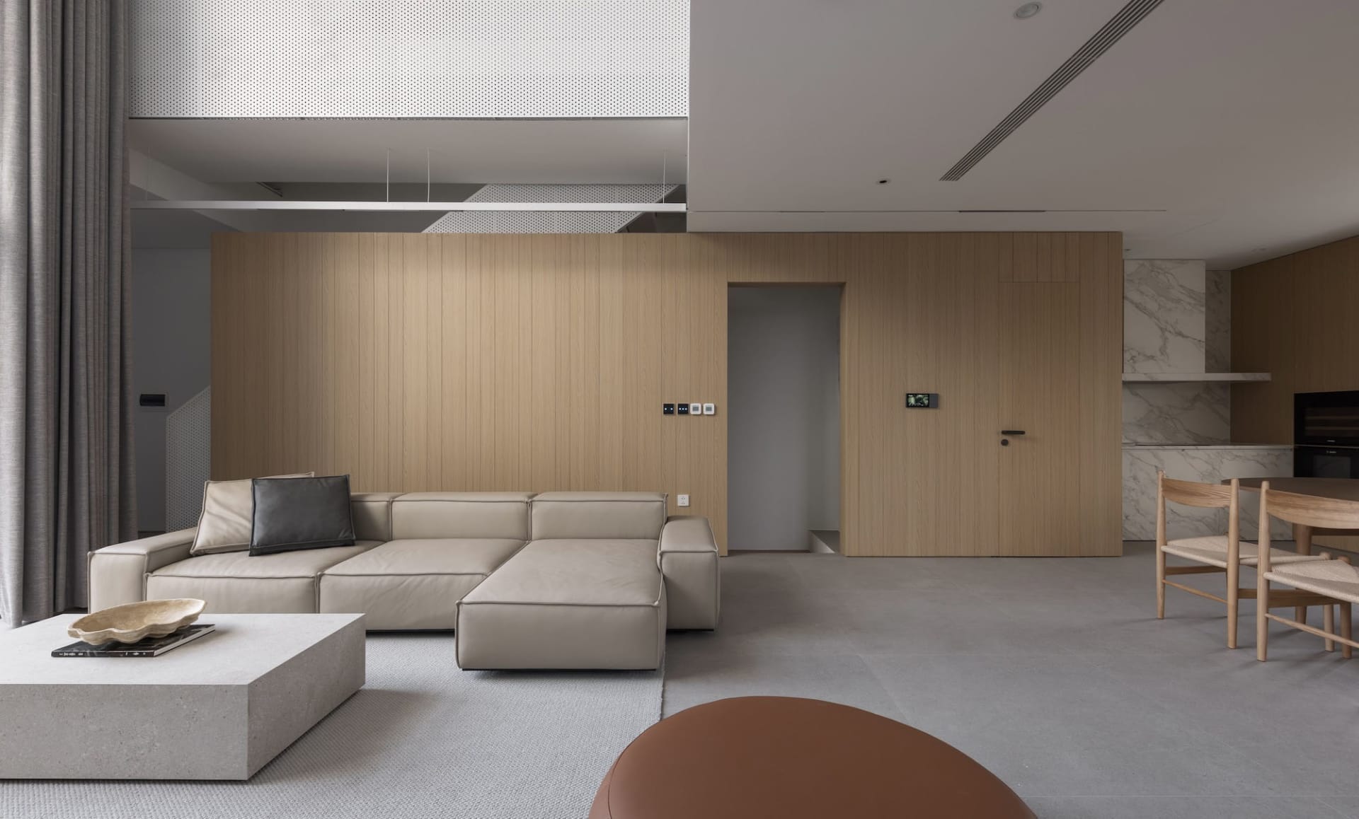 Modern minimalist living room featuring a concrete floor, a wooden wall, and a comfortable beige sectional sofa with a black