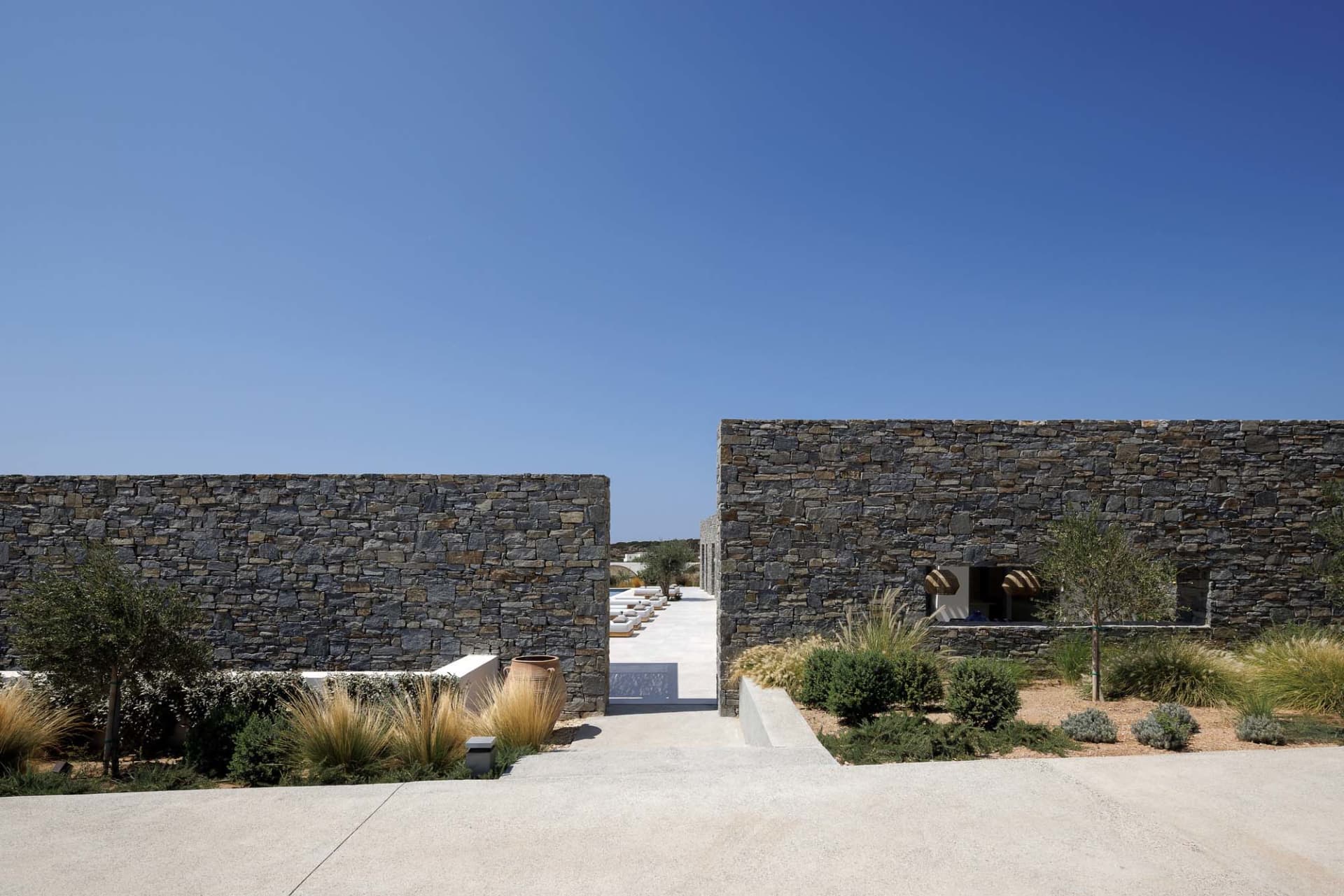 A modern residential exterior featuring stone walls and a clear blue sky.