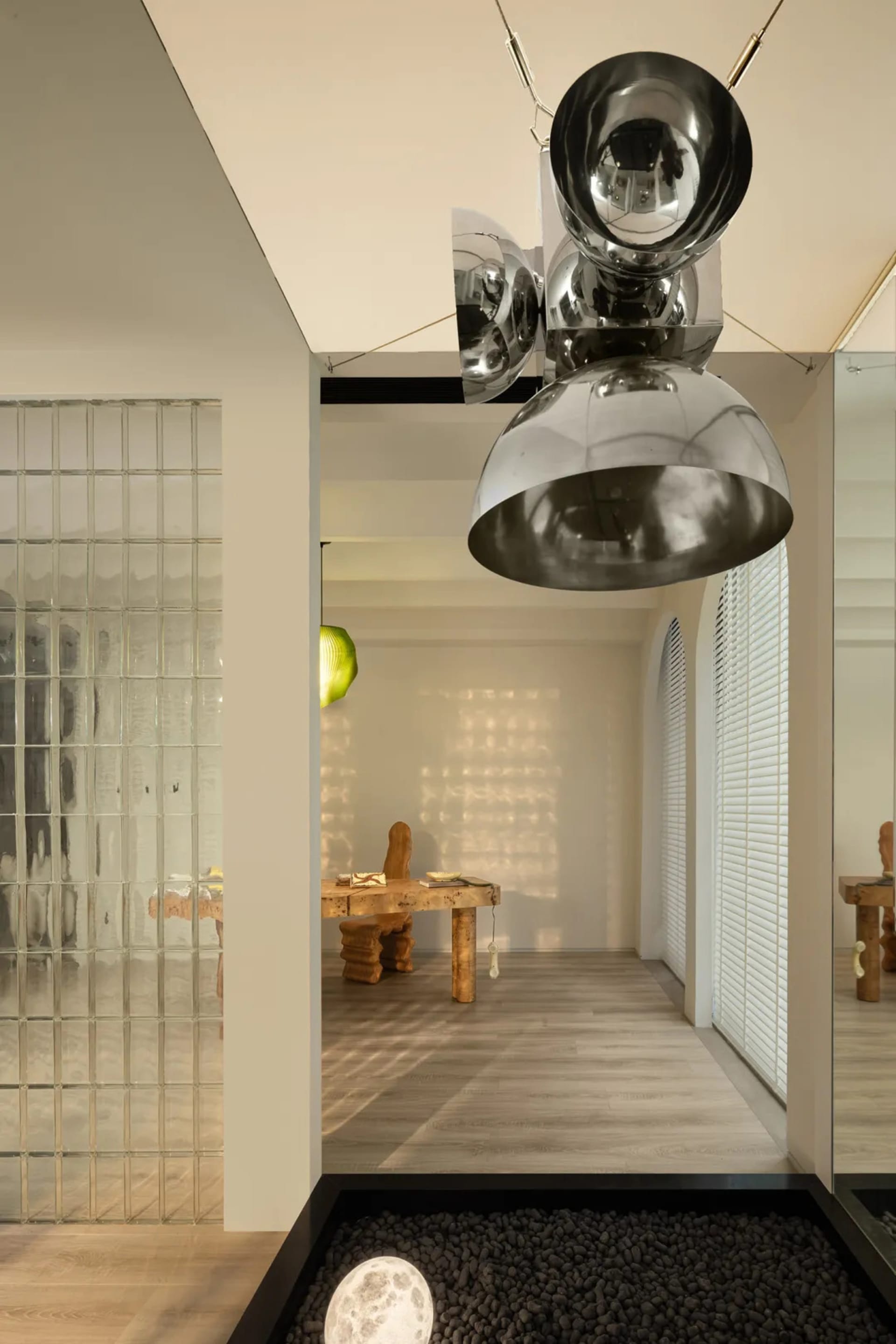Modern minimalist living room with metallic spherical chandelier and textured glass panels.
