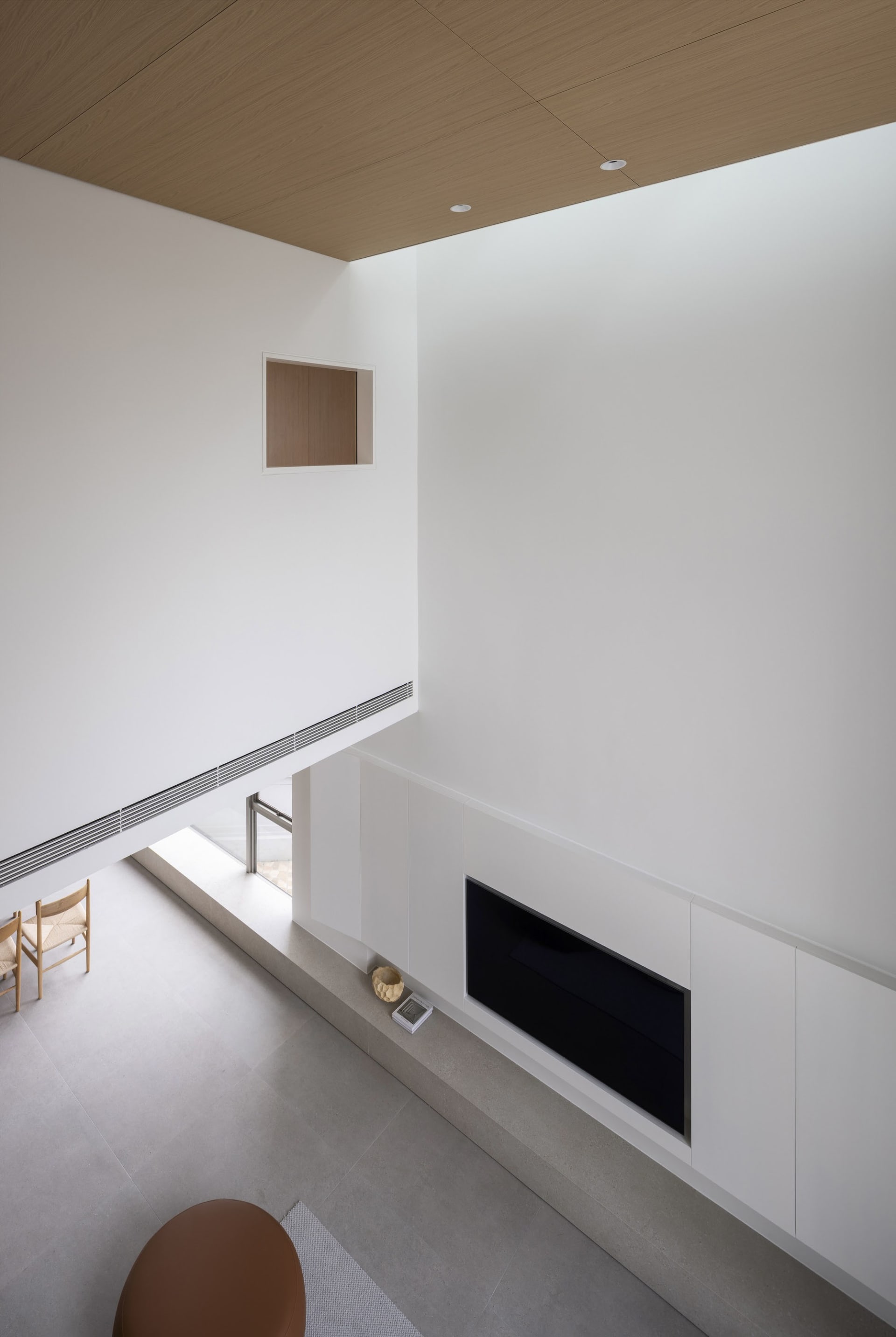 A minimalist living room with white concrete walls, wood ceiling, and a sleek fireplace.