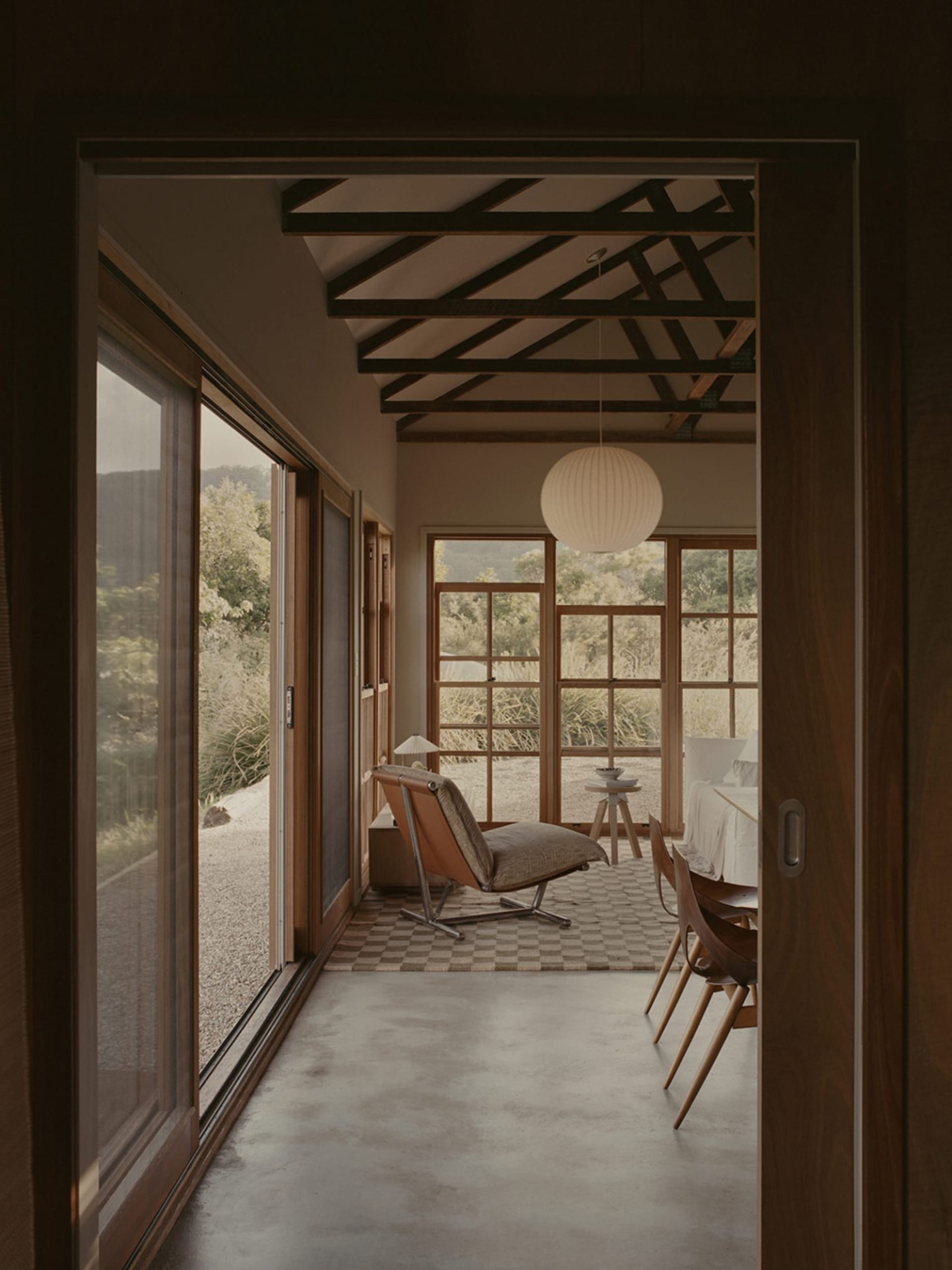 A minimalist living room with wooden furniture and concrete flooring.