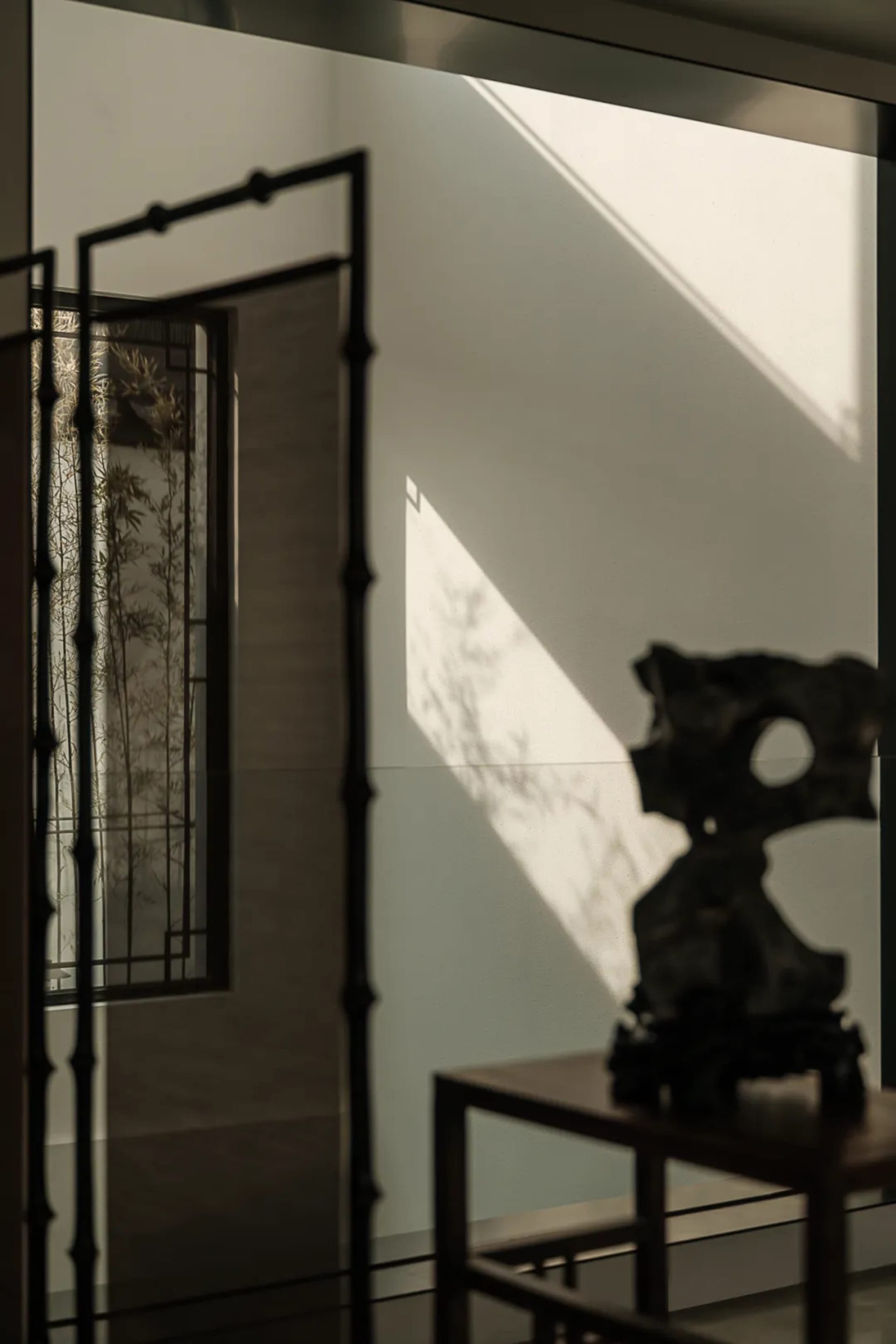 A modern entryway with wooden features and a shadowed bamboo plant in the background.