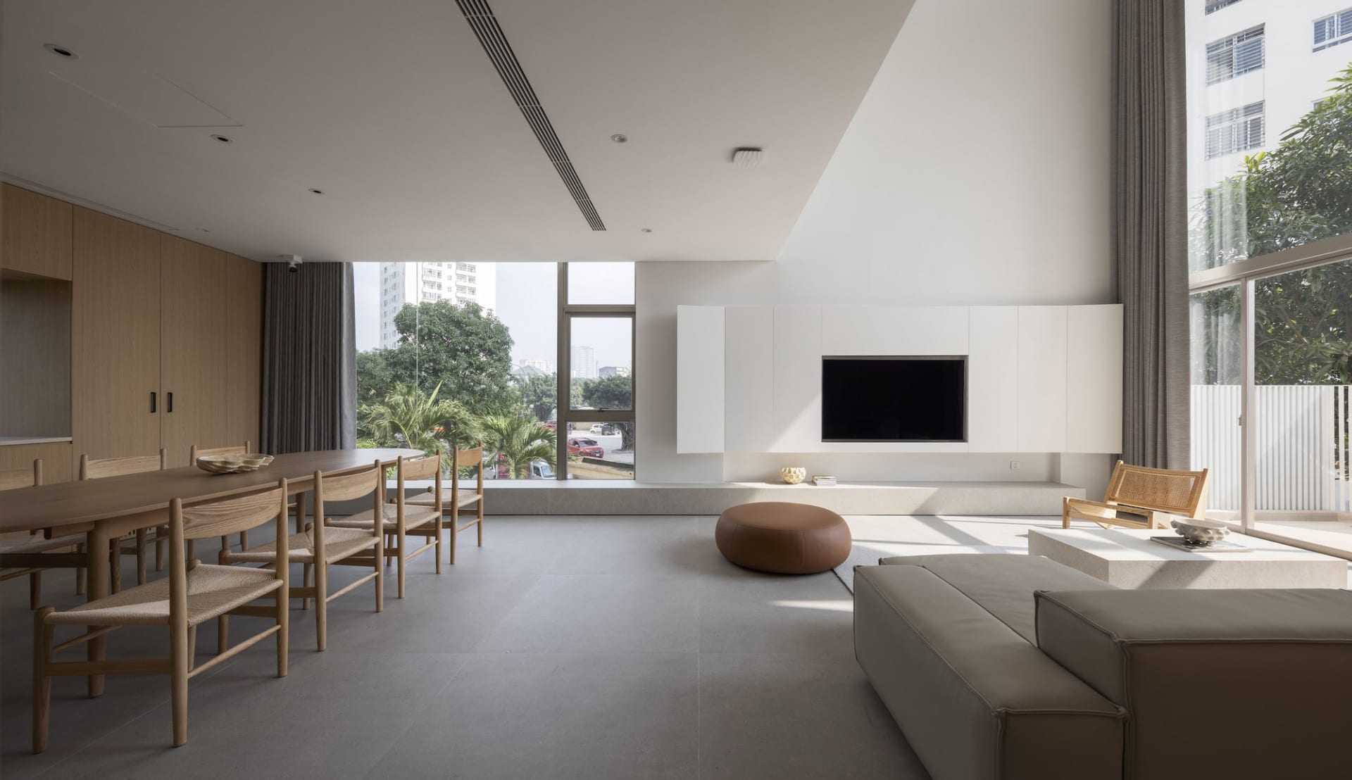 A modern living room featuring minimalistic furniture and a large wooden table with chairs.