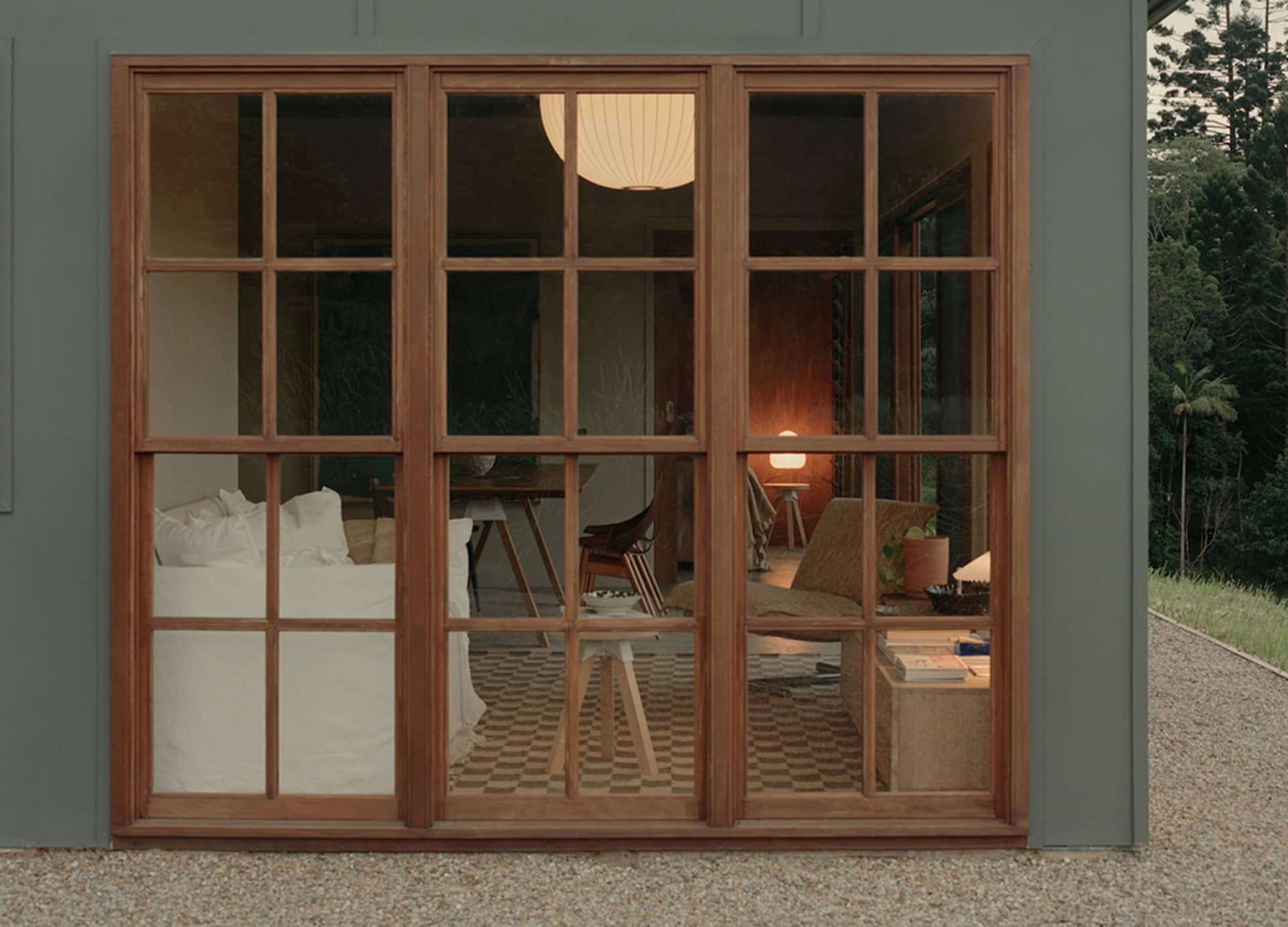A cozy, modern residential space with wooden walls, a mix of white and dark wooden furniture, and a warm, inviting atmosphere