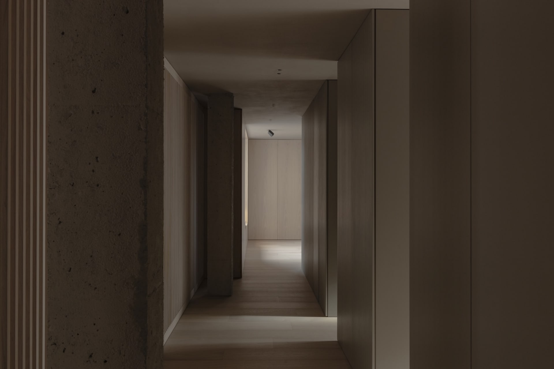 A minimalist hallway with wooden flooring and concrete walls.