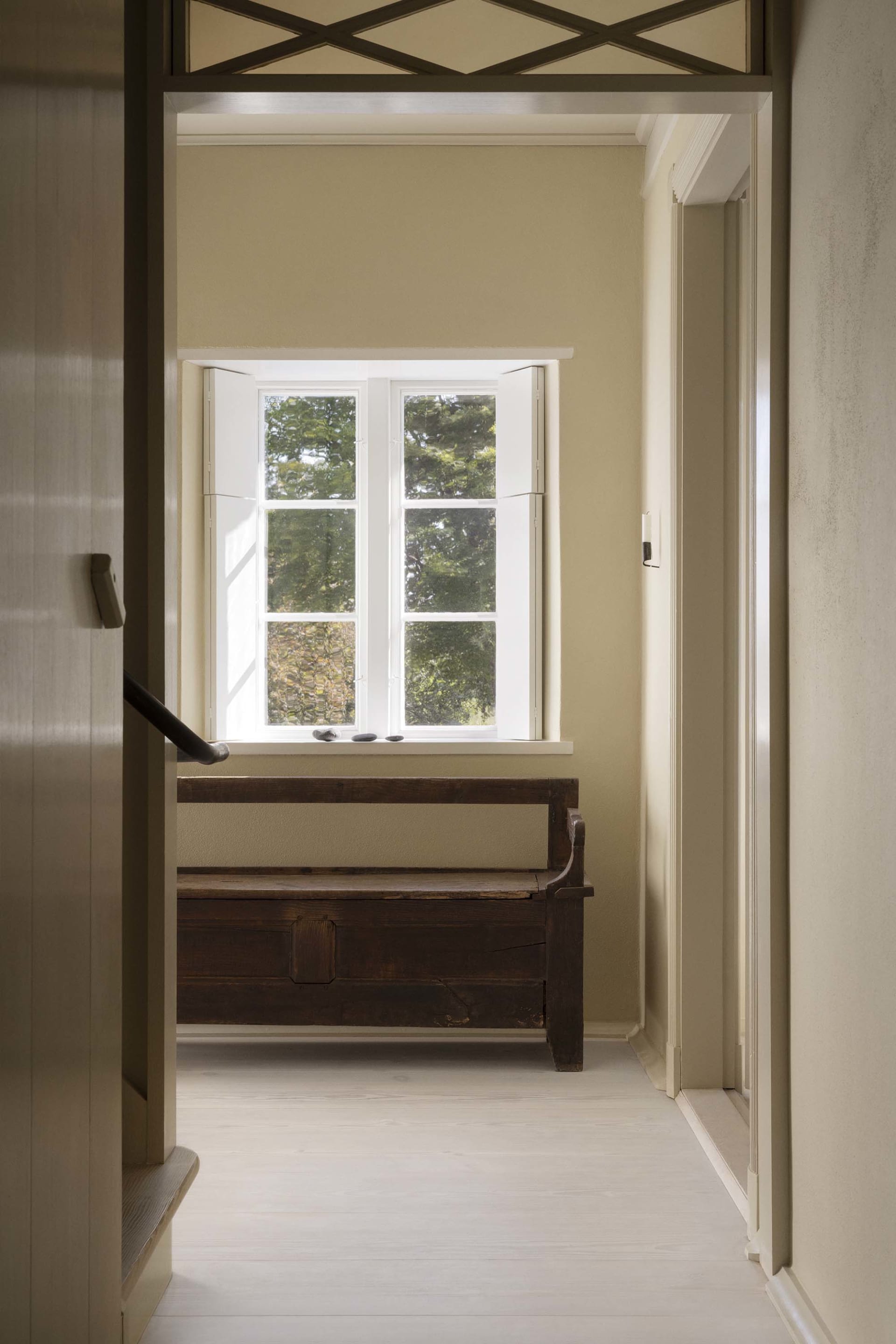 A minimalist window nook featuring wooden furniture and a view of a wooded area.