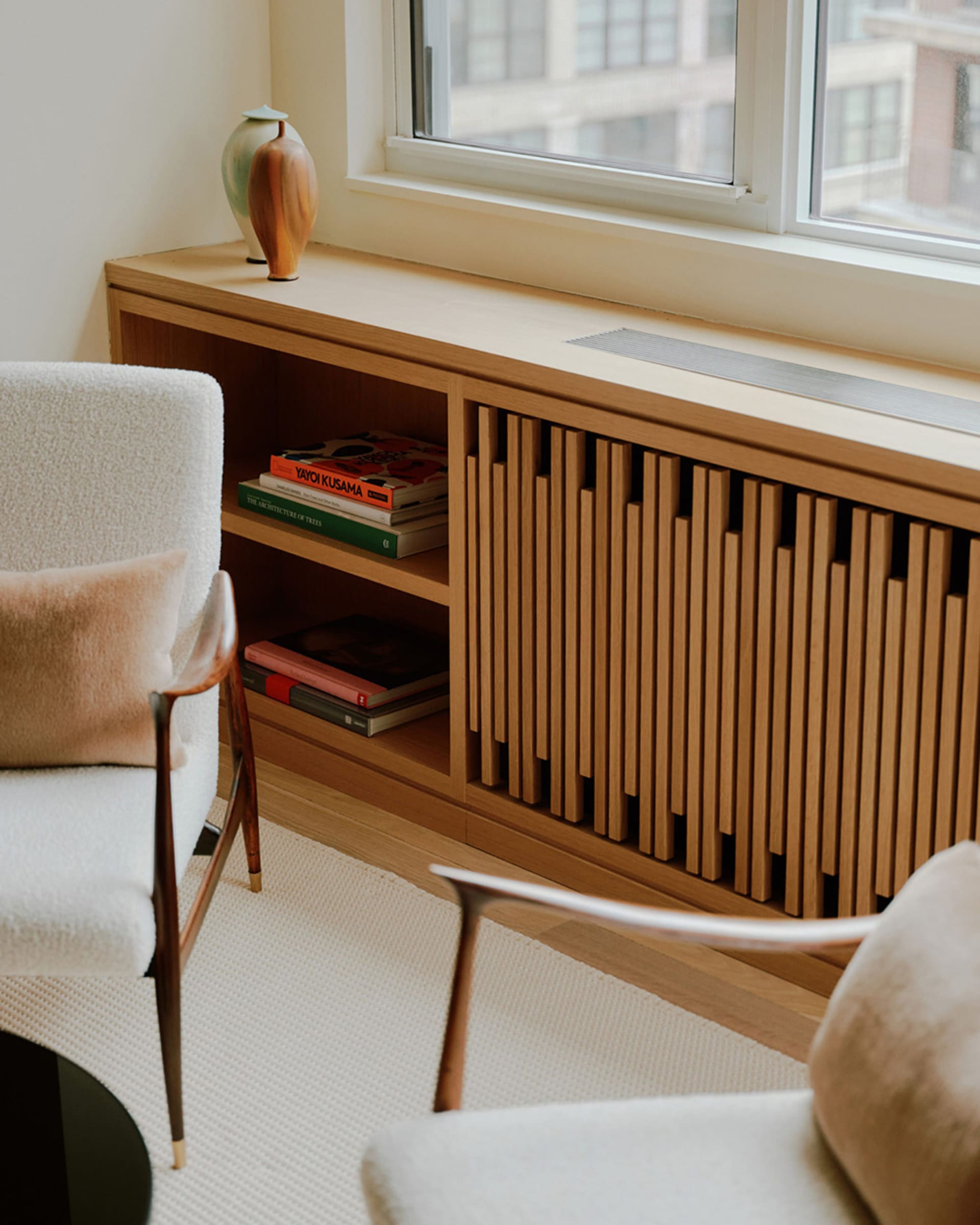 A modern interior design featuring wooden shelving and a window with books and a vase on the sill.