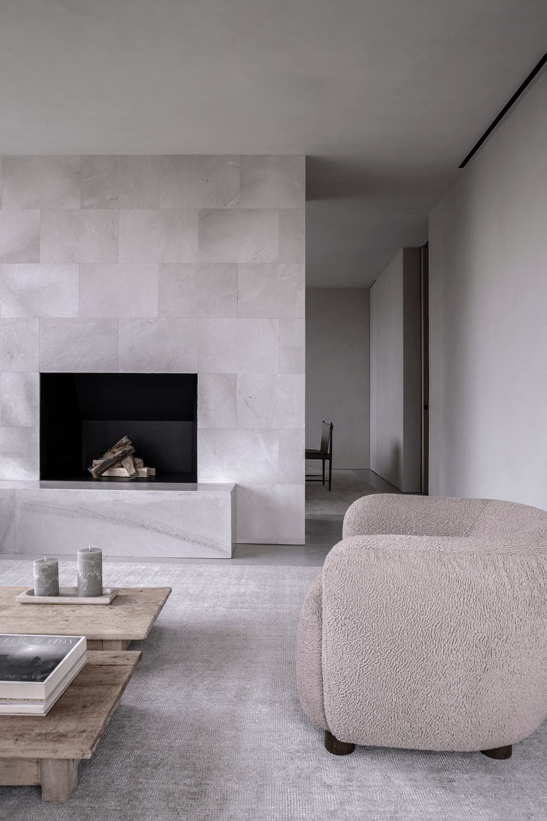 A modern living room with a concrete fireplace and a textured armchair.