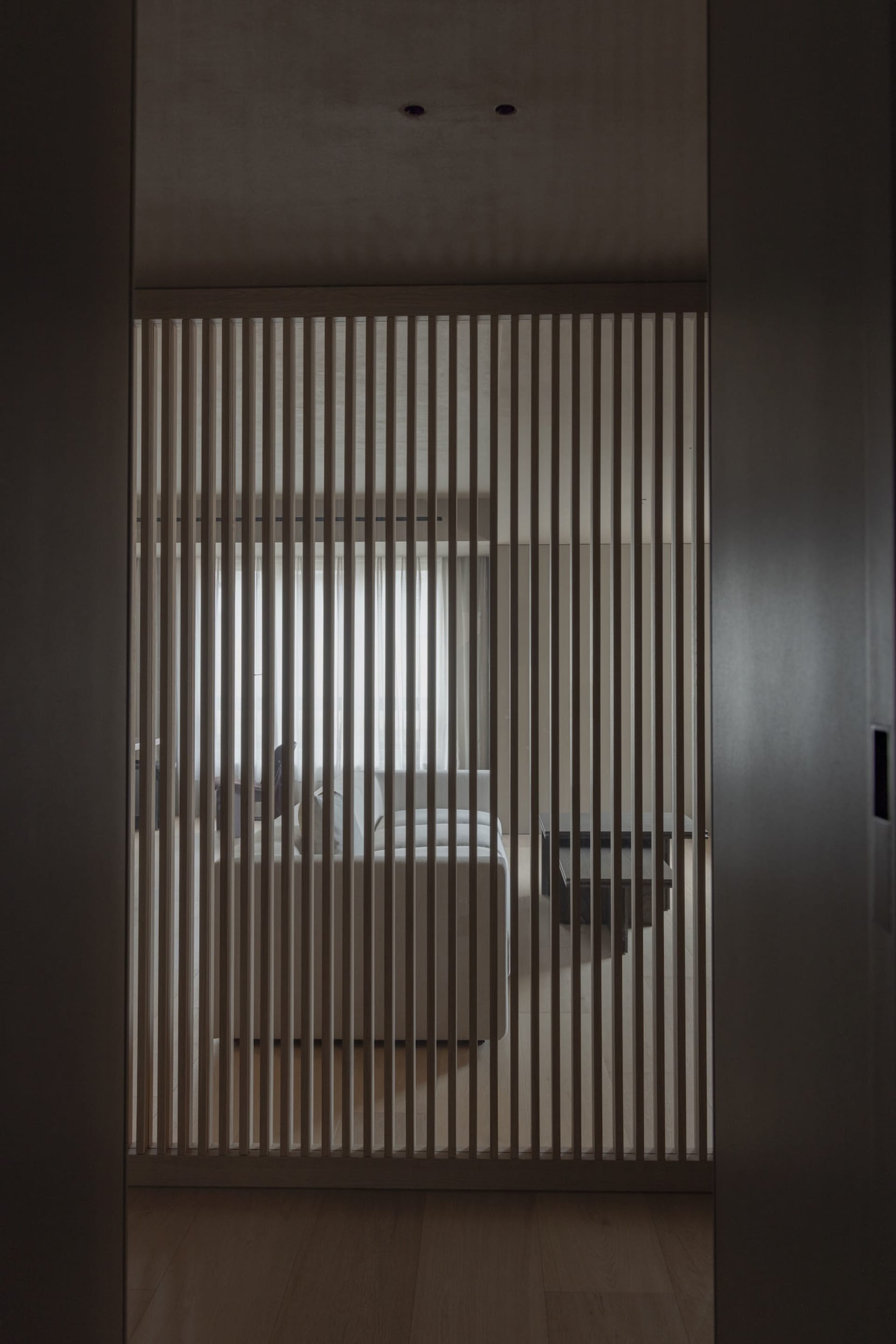 A view of a minimalist bedroom with a wooden room divider.