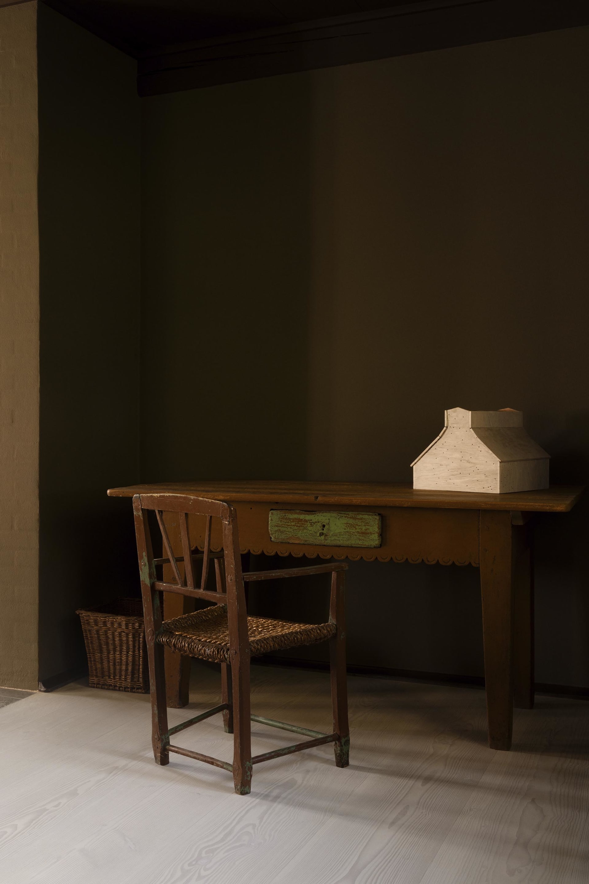 A rustic wooden table and chair in a cozy home office setting.