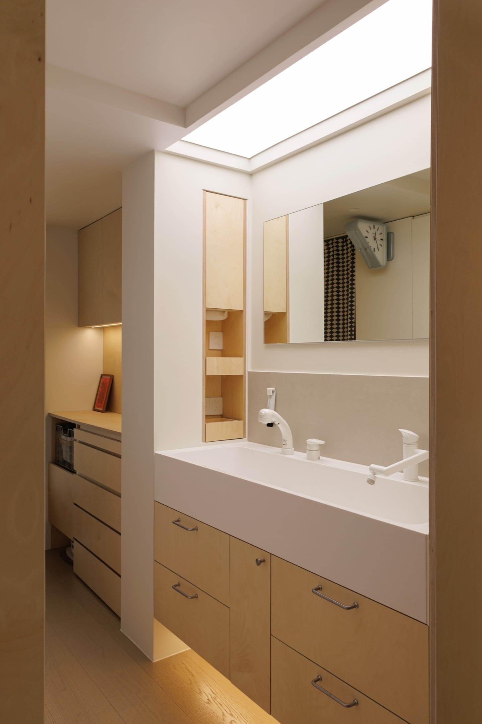 Modern minimalist bathroom with a white porcelain sink and wooden cabinets