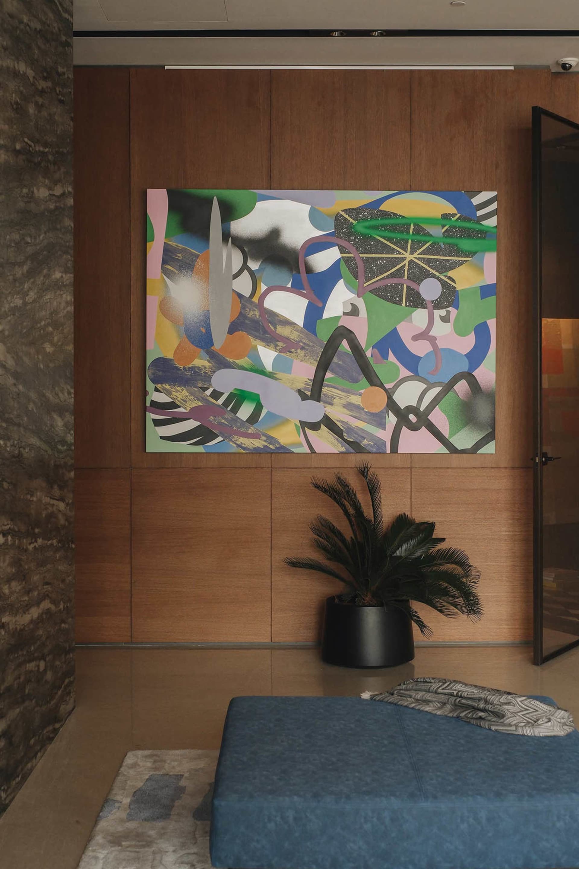 A modern living room features an abstract painting hanging on wood-paneled walls, creating a contemporary and stylish atmosph