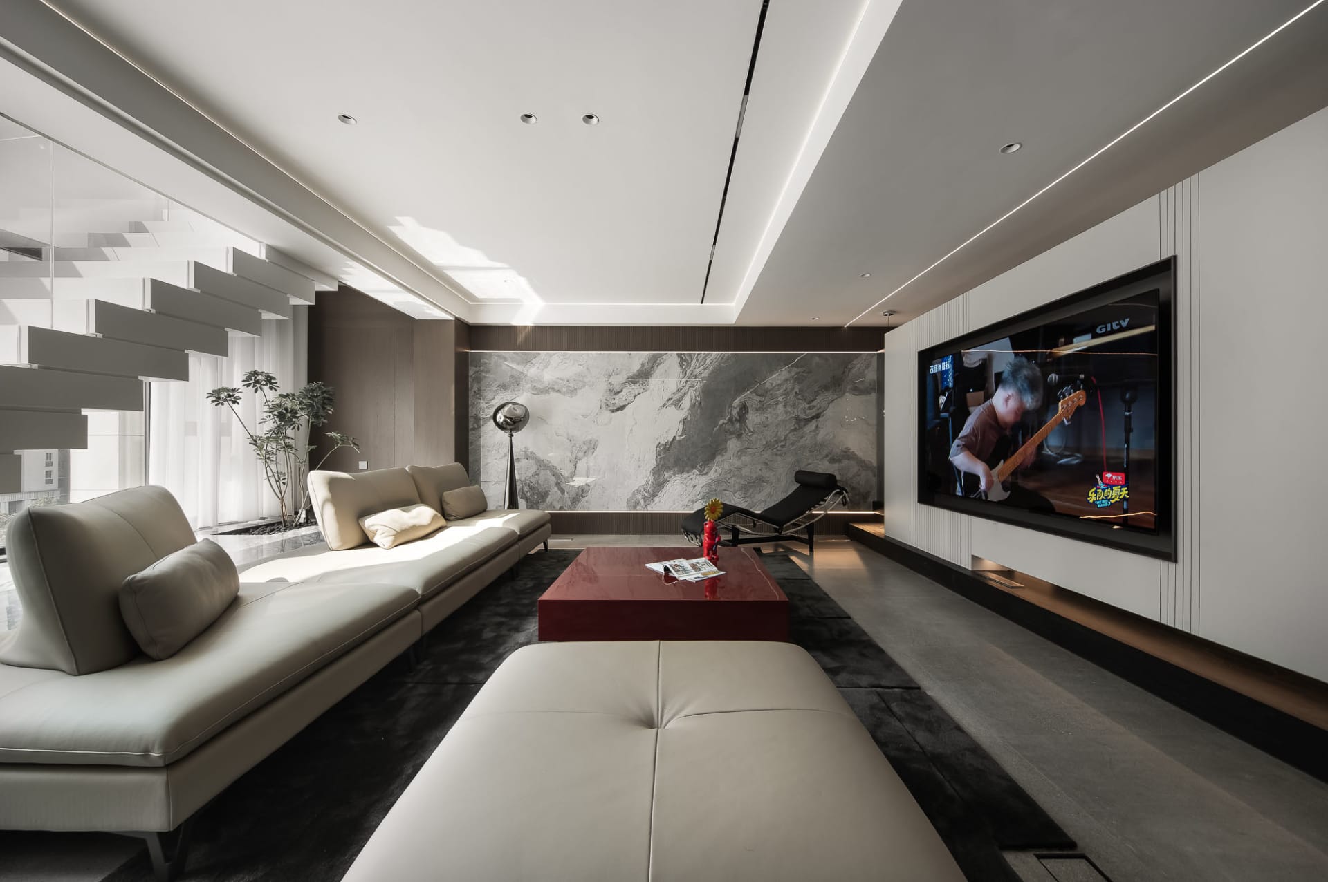 A modern living room featuring a concrete wall and a red coffee table.