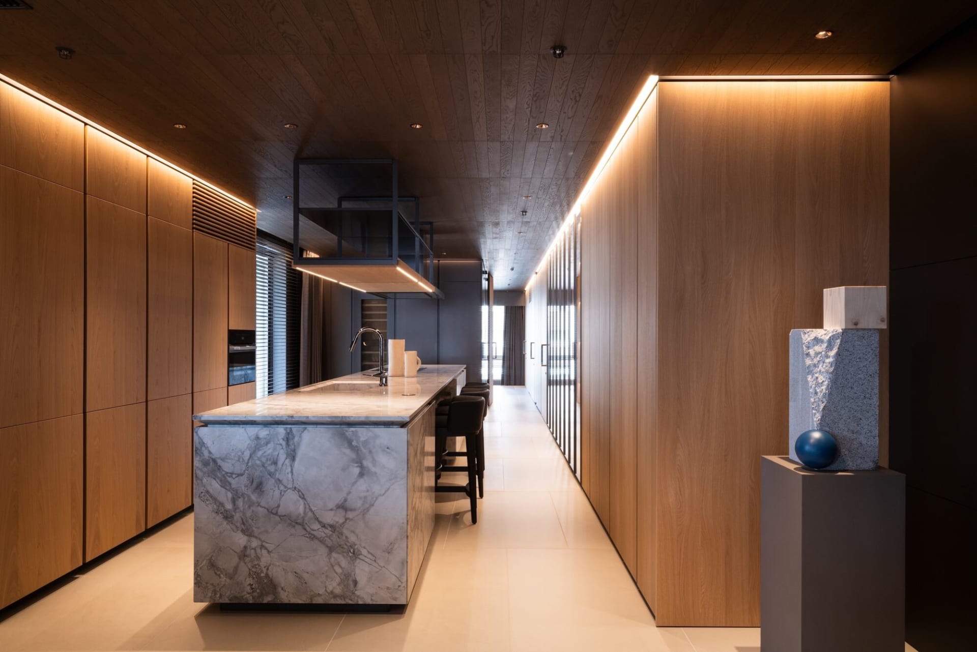 Modern, minimalist kitchen with wooden cabinets and marble countertops.
