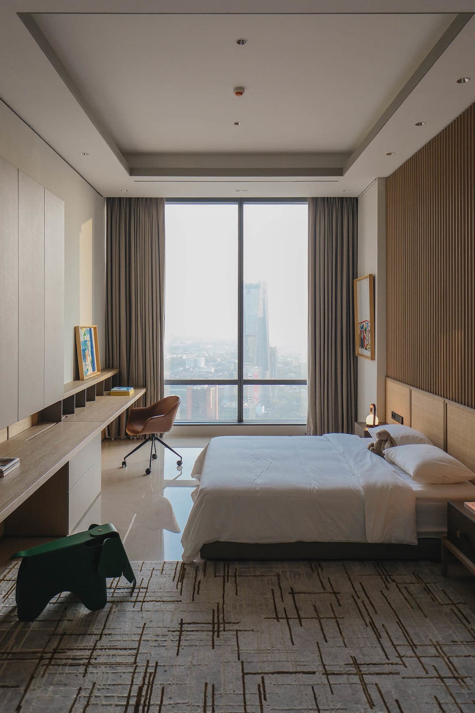 A minimalist bedroom with a grey bed and curtains, large window, and modern furniture.