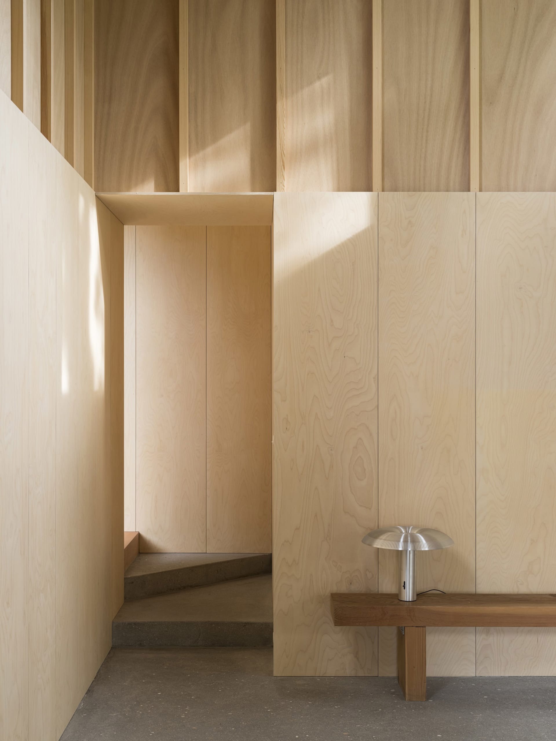 Modern entryway featuring minimalist design, wood paneling, and concrete flooring.