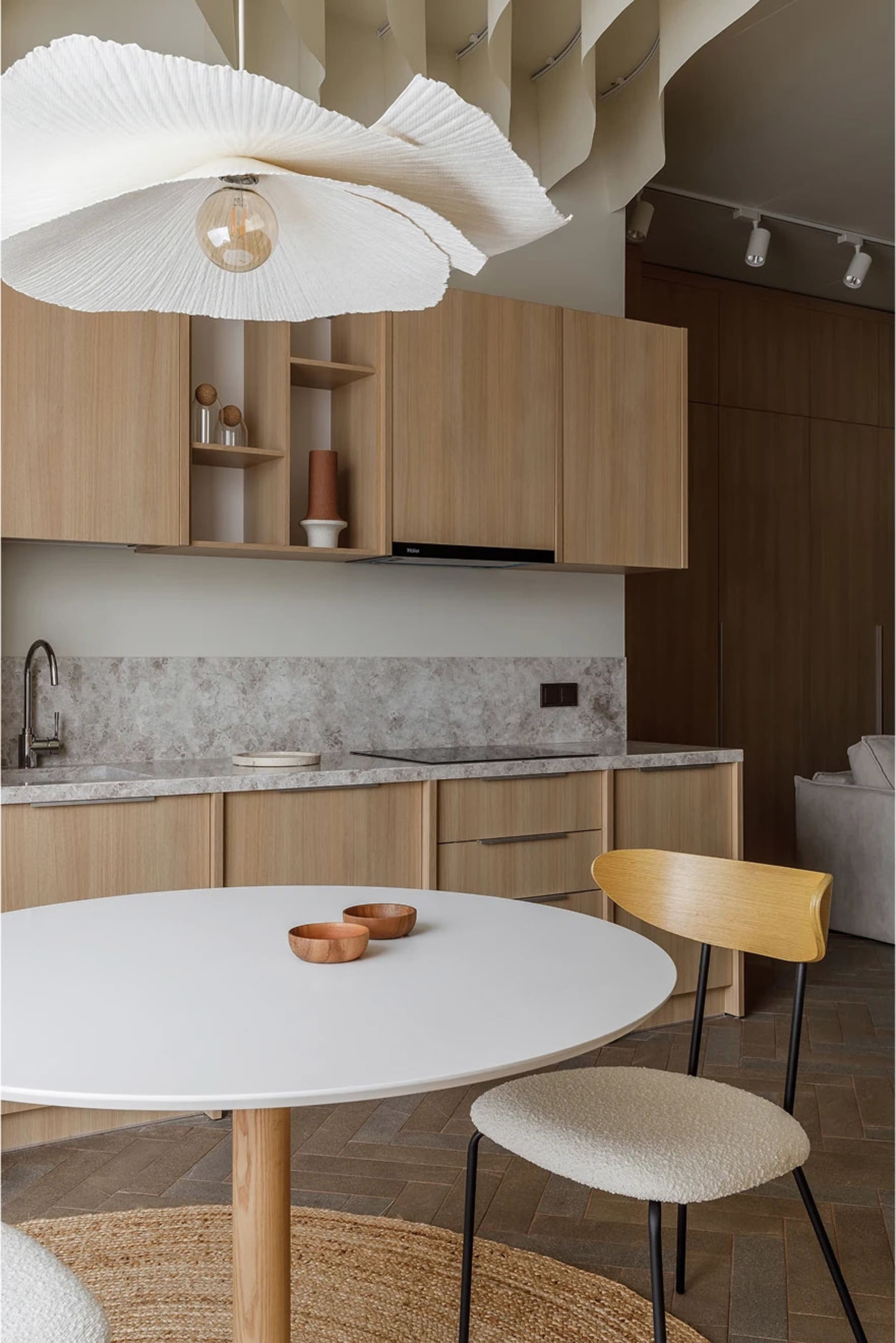 Modern kitchen with minimalist design, featuring wooden cabinets and a marble countertop.