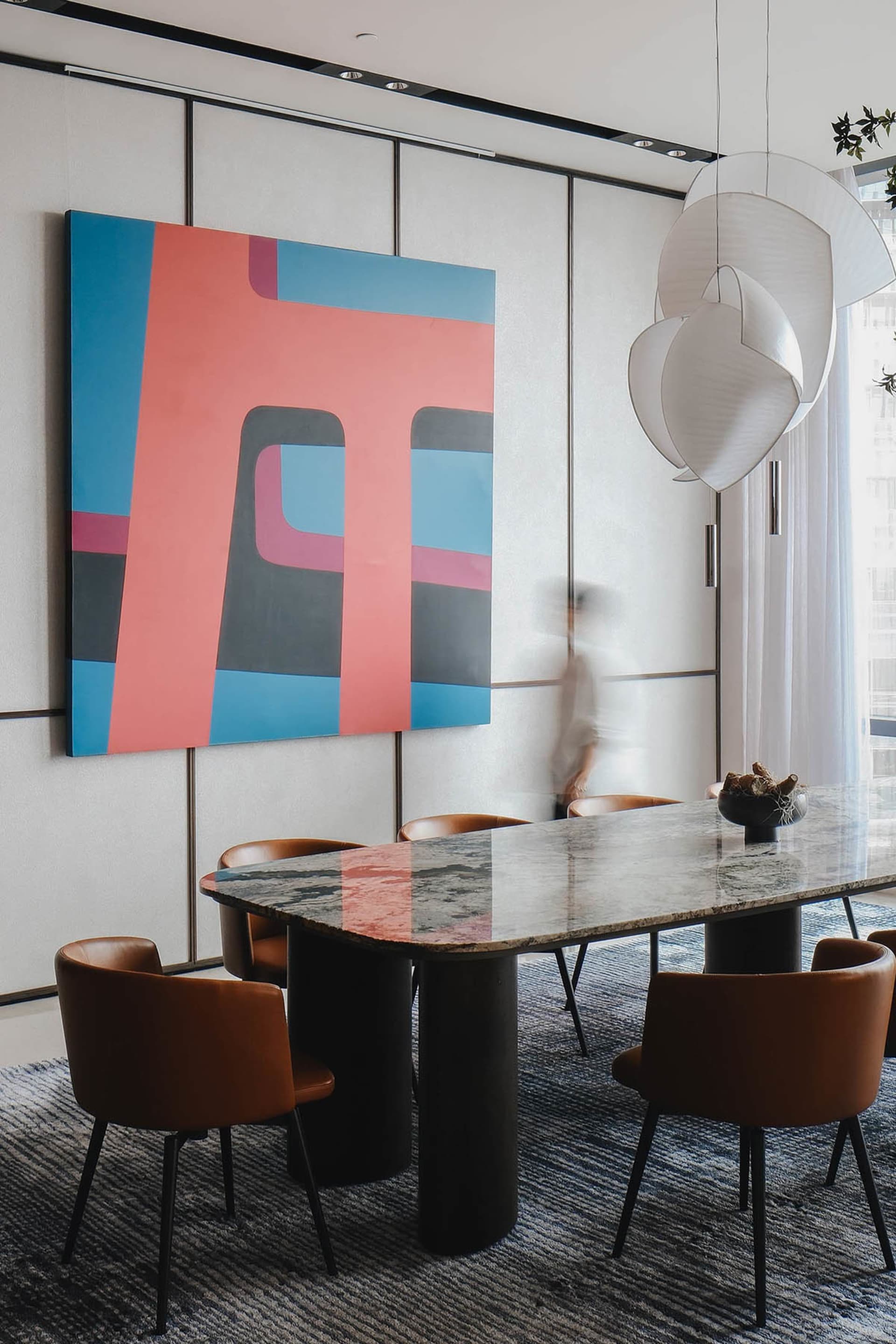 A modern dining room features a granite-top table with concrete legs and stylized, abstract art on the wall.