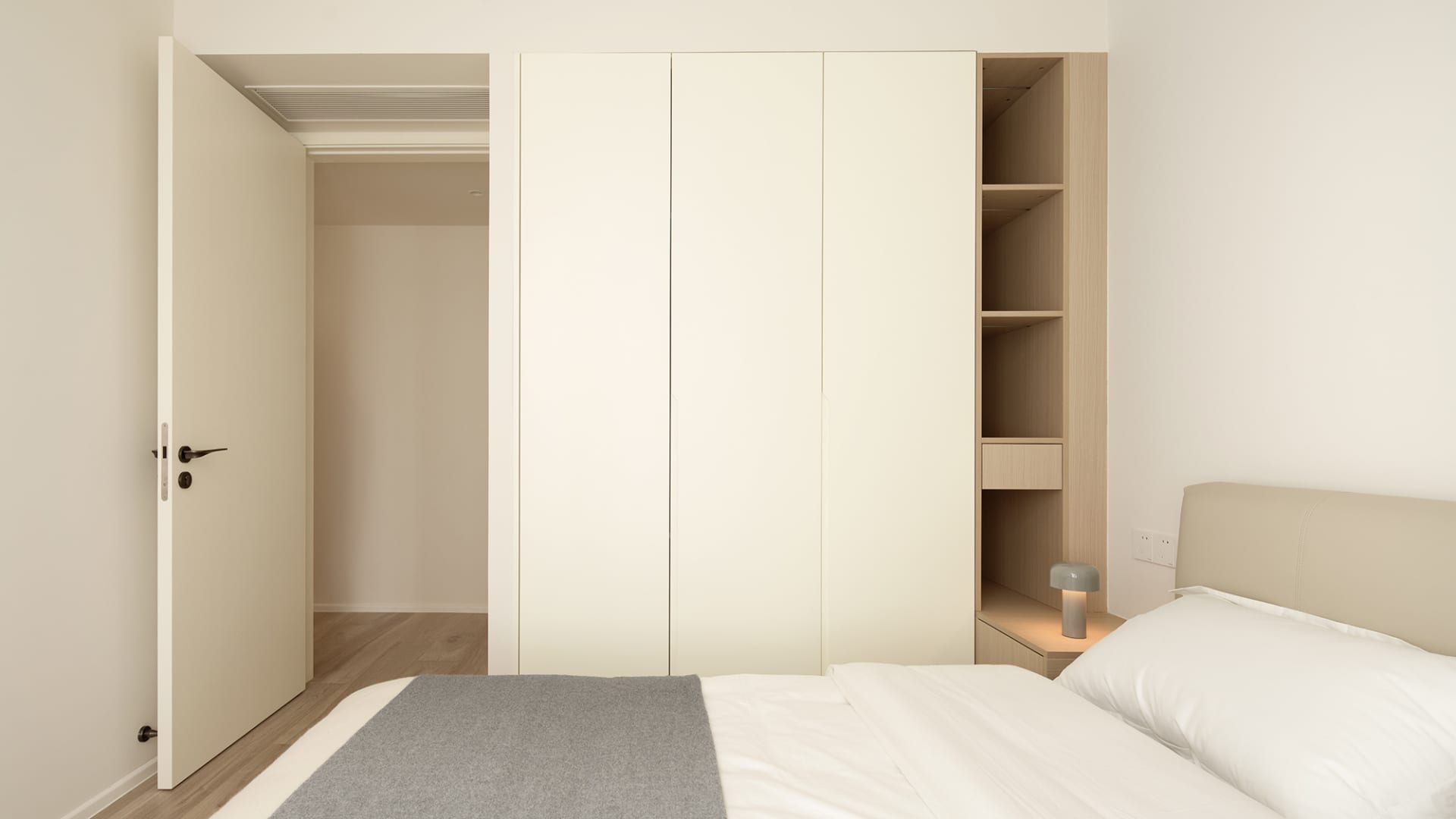 Modern minimalist bedroom with white furniture and fabric coverings.