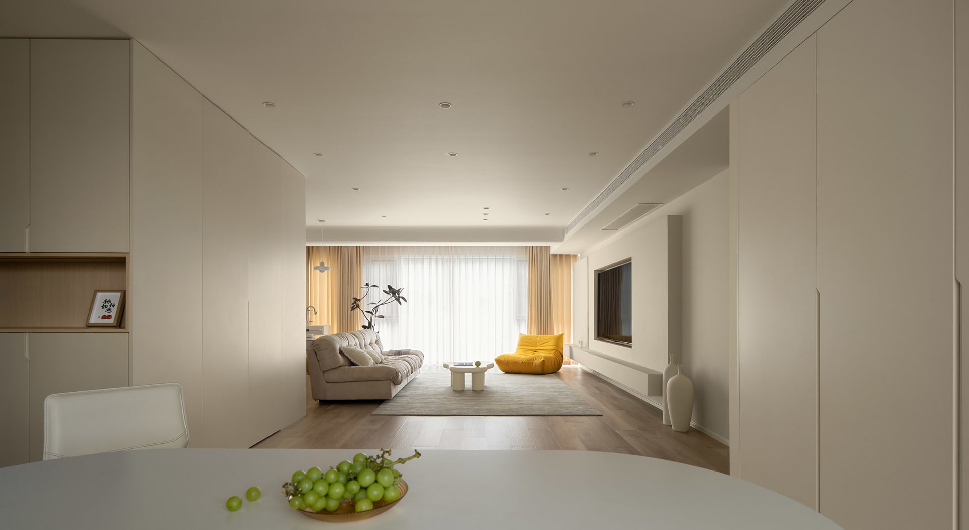 Modern minimalist living room with wood flooring, fabric sofa, and yellow accent chair.