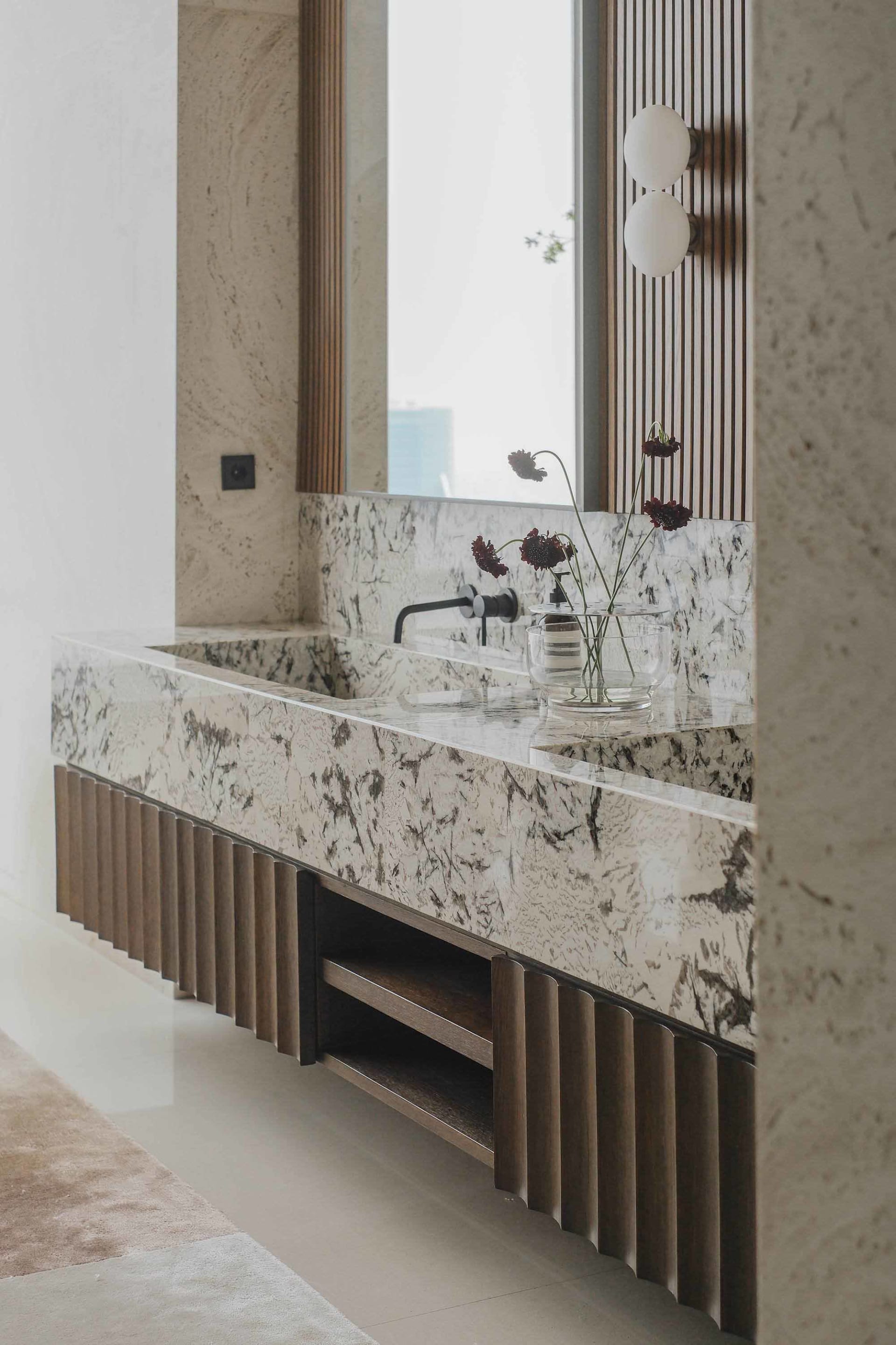Modern bathroom featuring a granite countertop with a sleek, contemporary faucet and a vase of flowers.