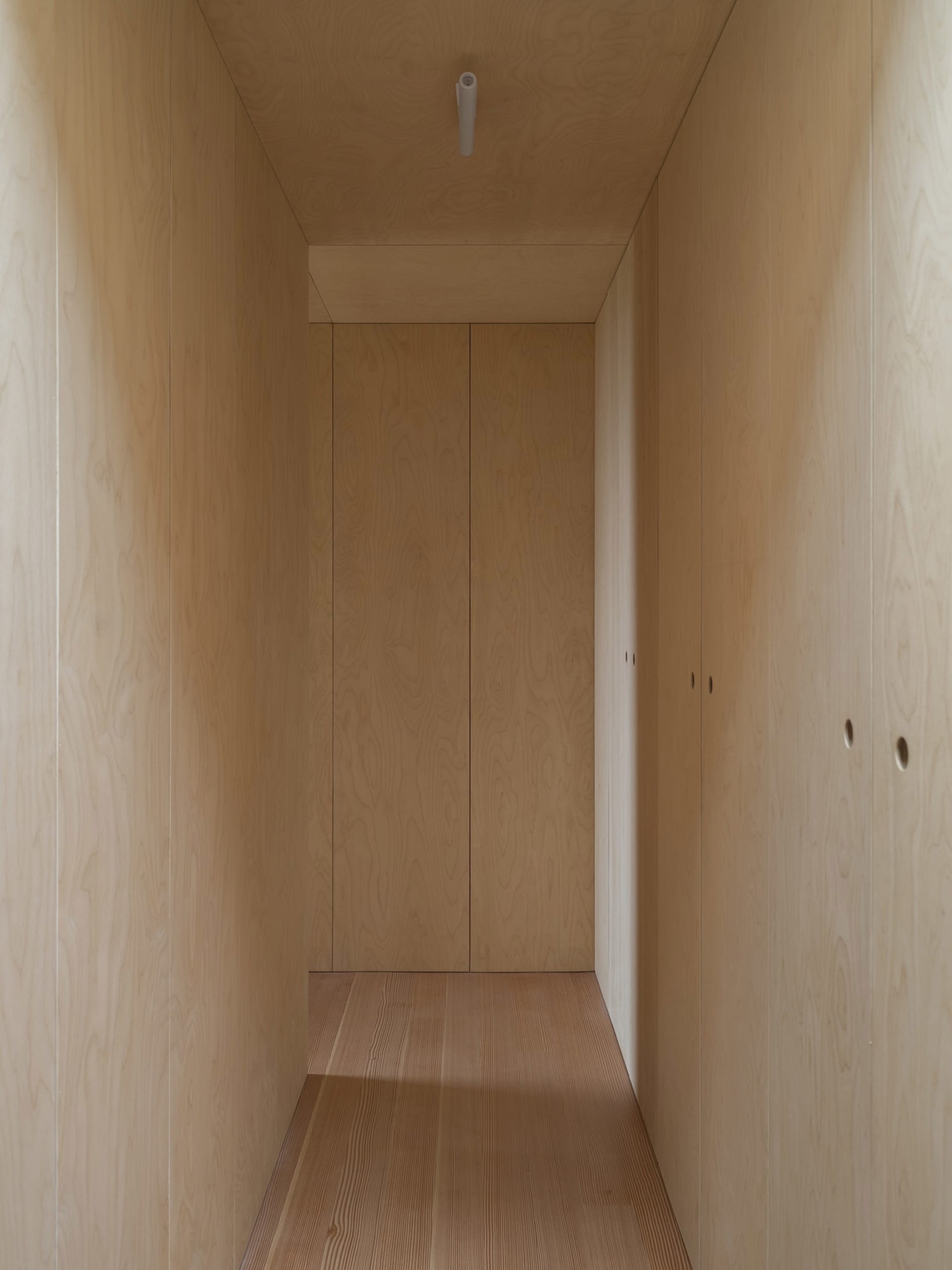 A modern closet with wooden panels and a wooden floor.