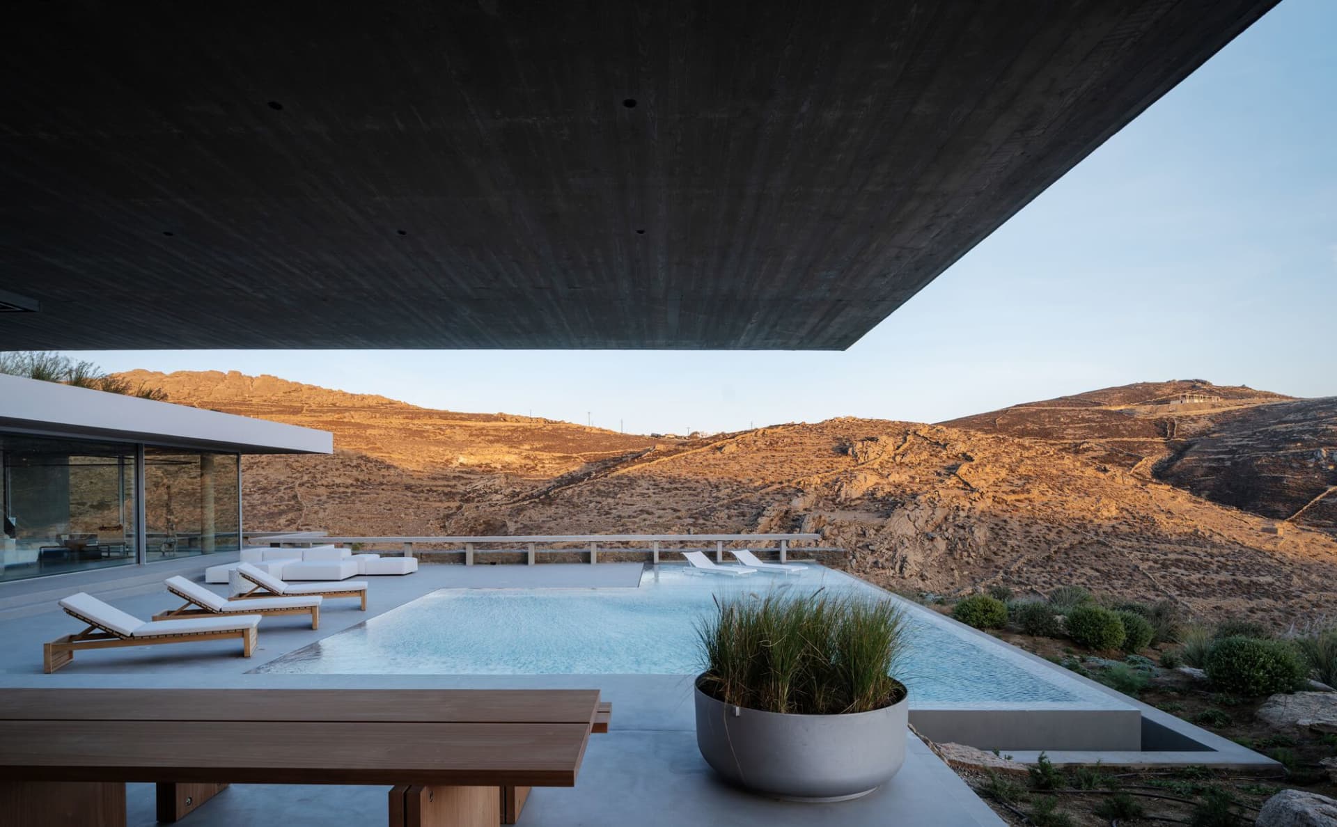 Modern luxury house with concrete pool and view of rugged landscape