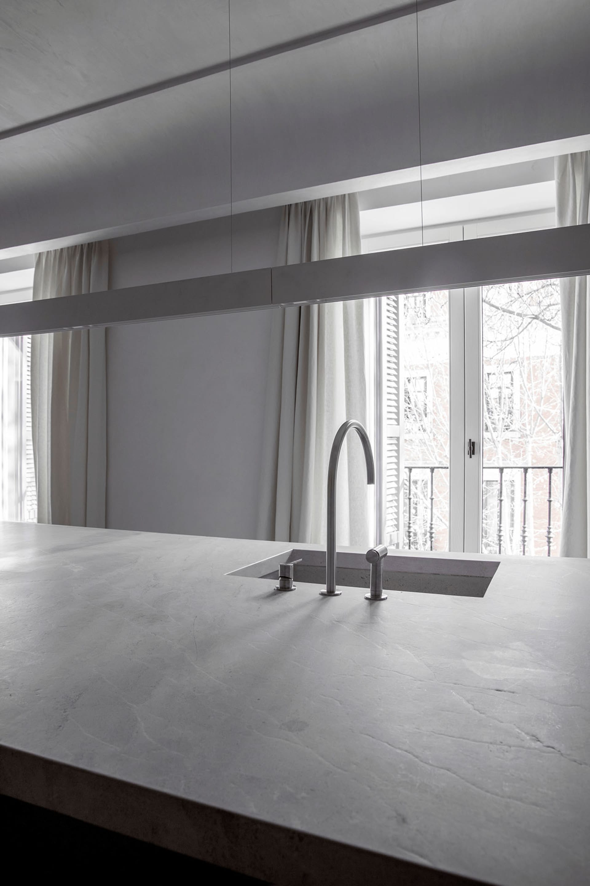A minimalist kitchen with a concrete countertop and a modern sink.