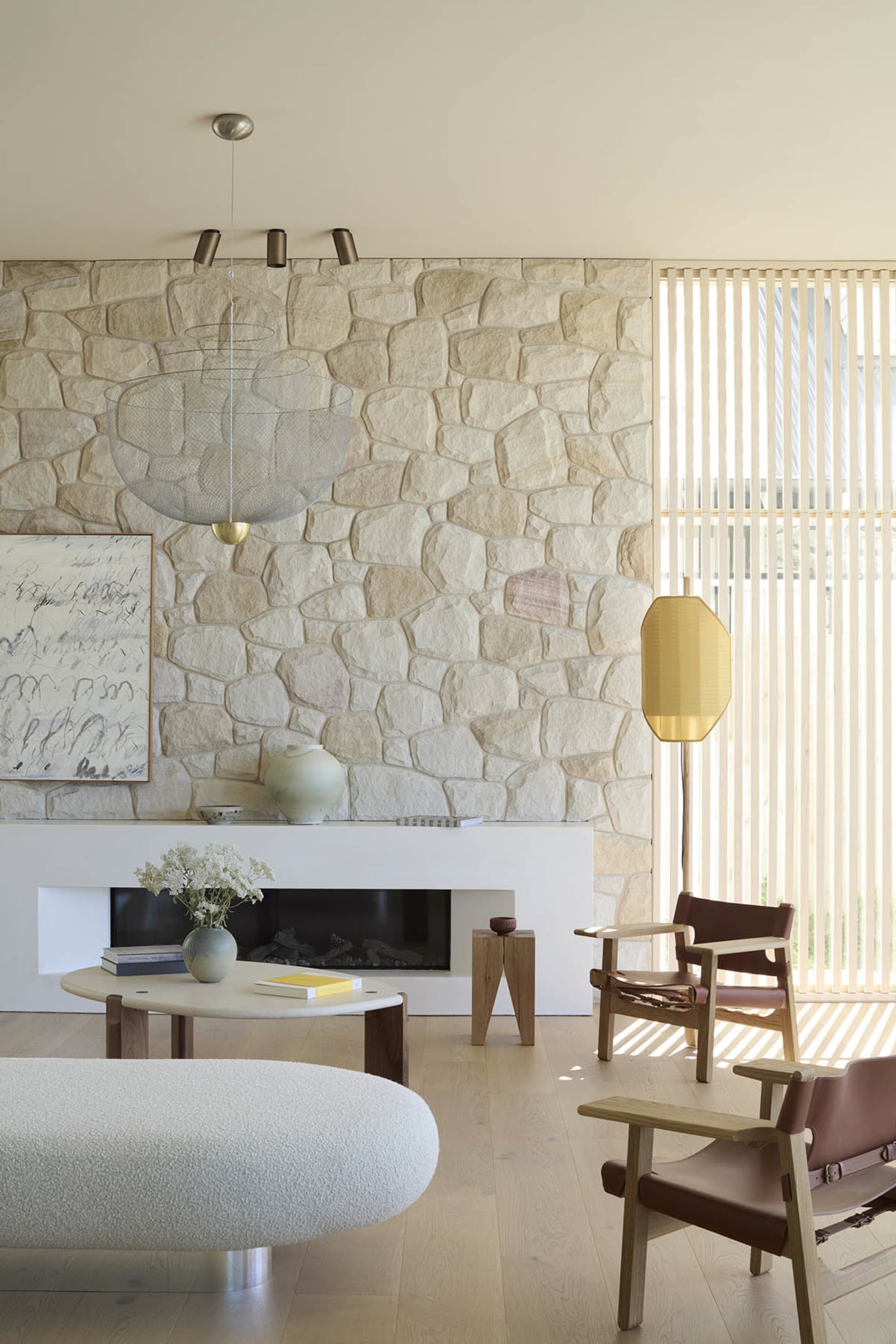 A minimalist living room with stone walls, wooden floors, and modern furniture.