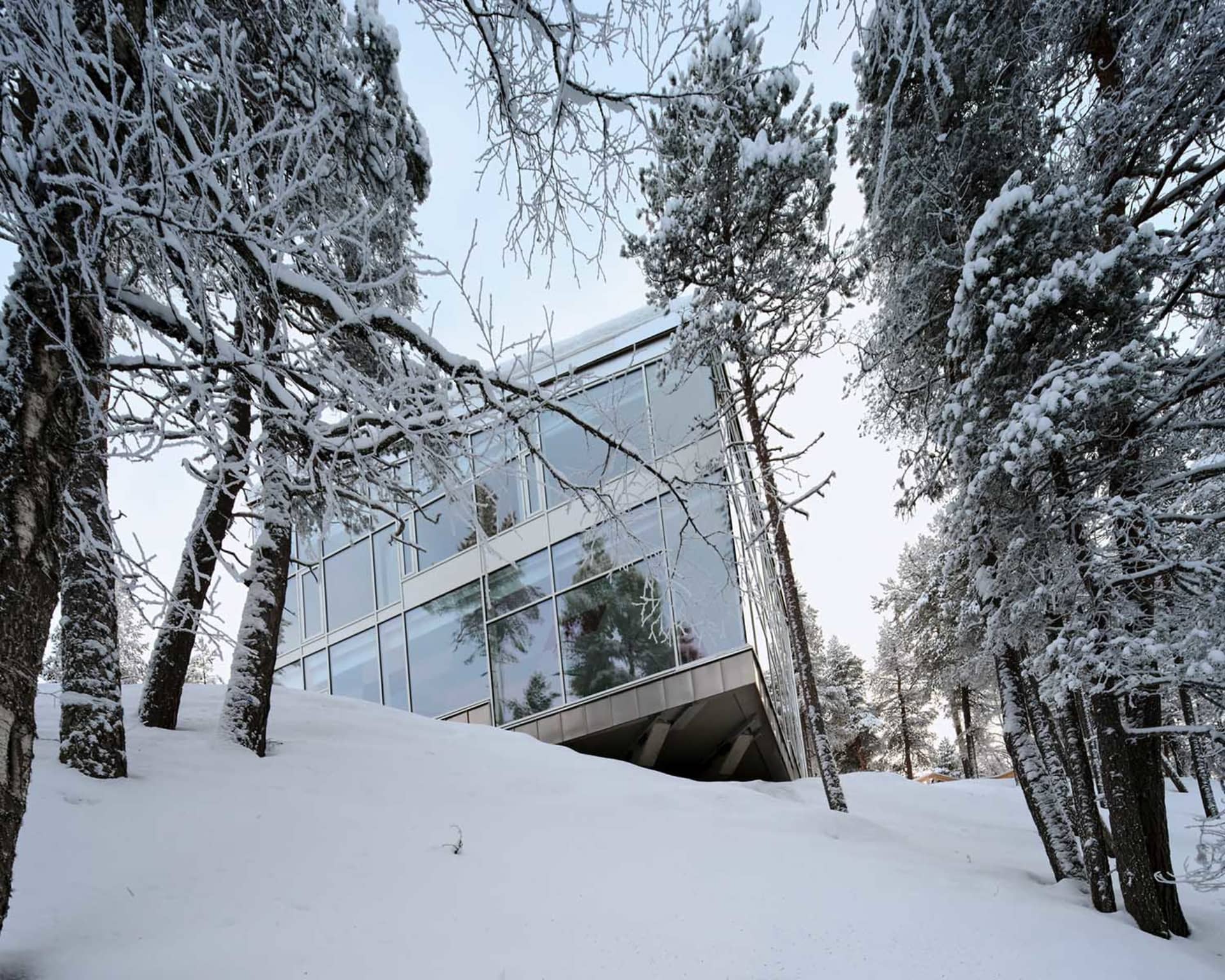一座流線型的現代建築,玻璃窗戶坐落在雪景之中。