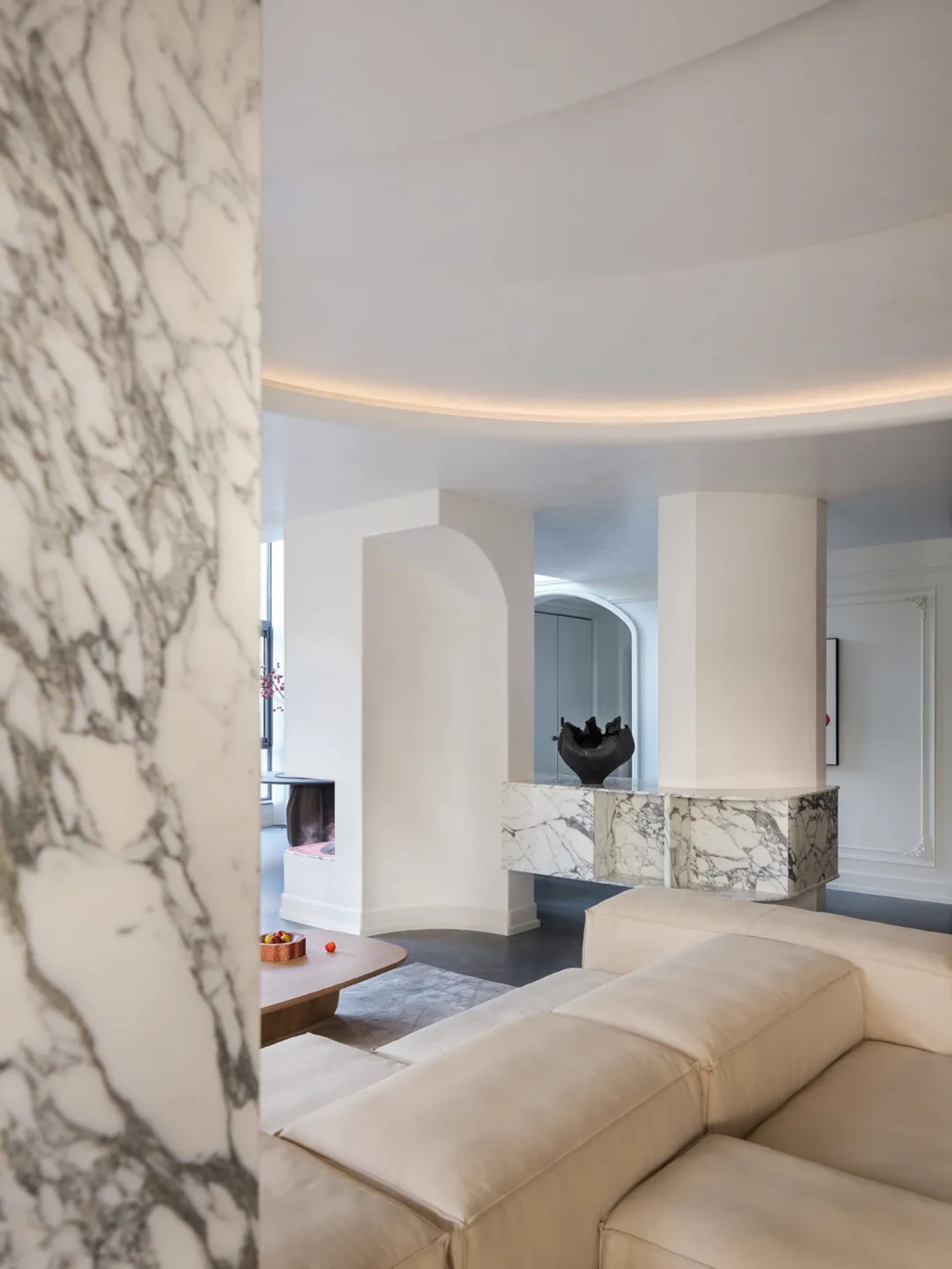 Modern minimalist living room with marble and white leather furniture, featuring a round window and a cozy seating area.