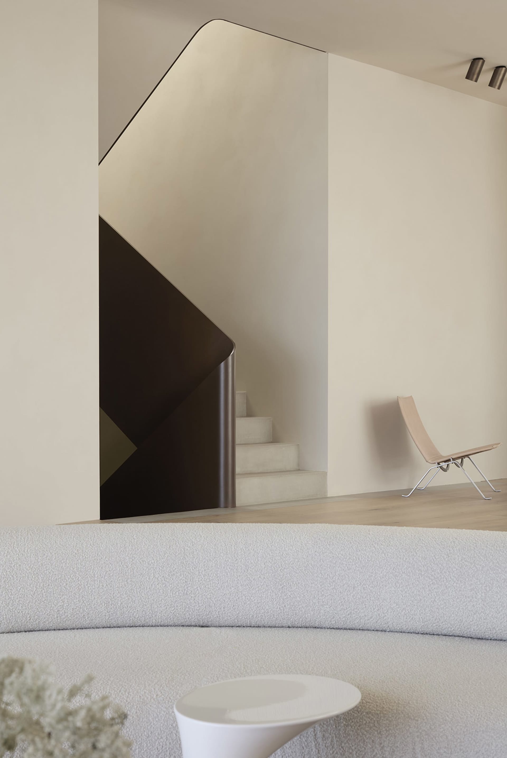 A modern living room featuring a white sofa and a sleek, white staircase.