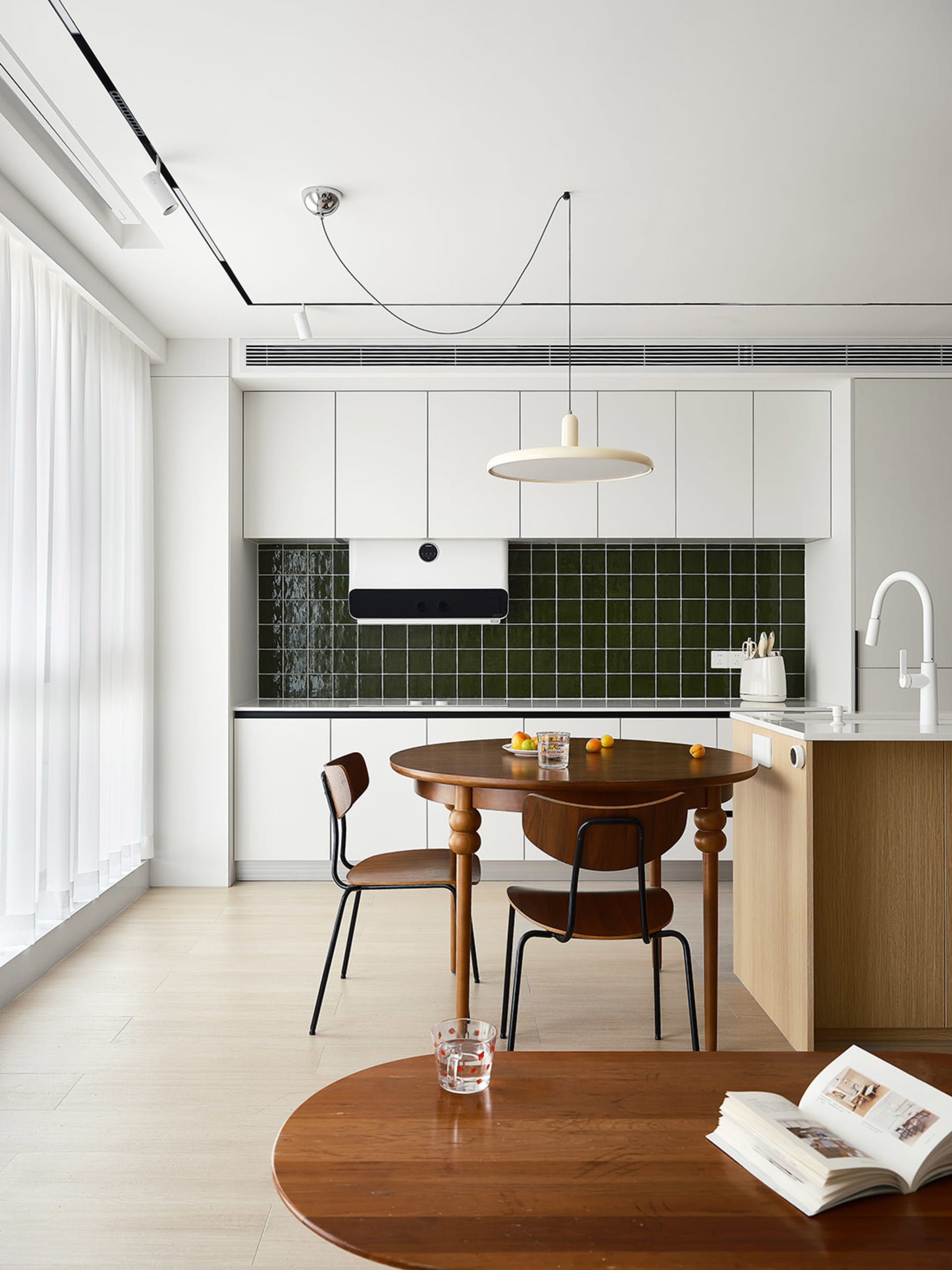A modern minimalist residential kitchen with wood cabinets and a green tile backsplash.