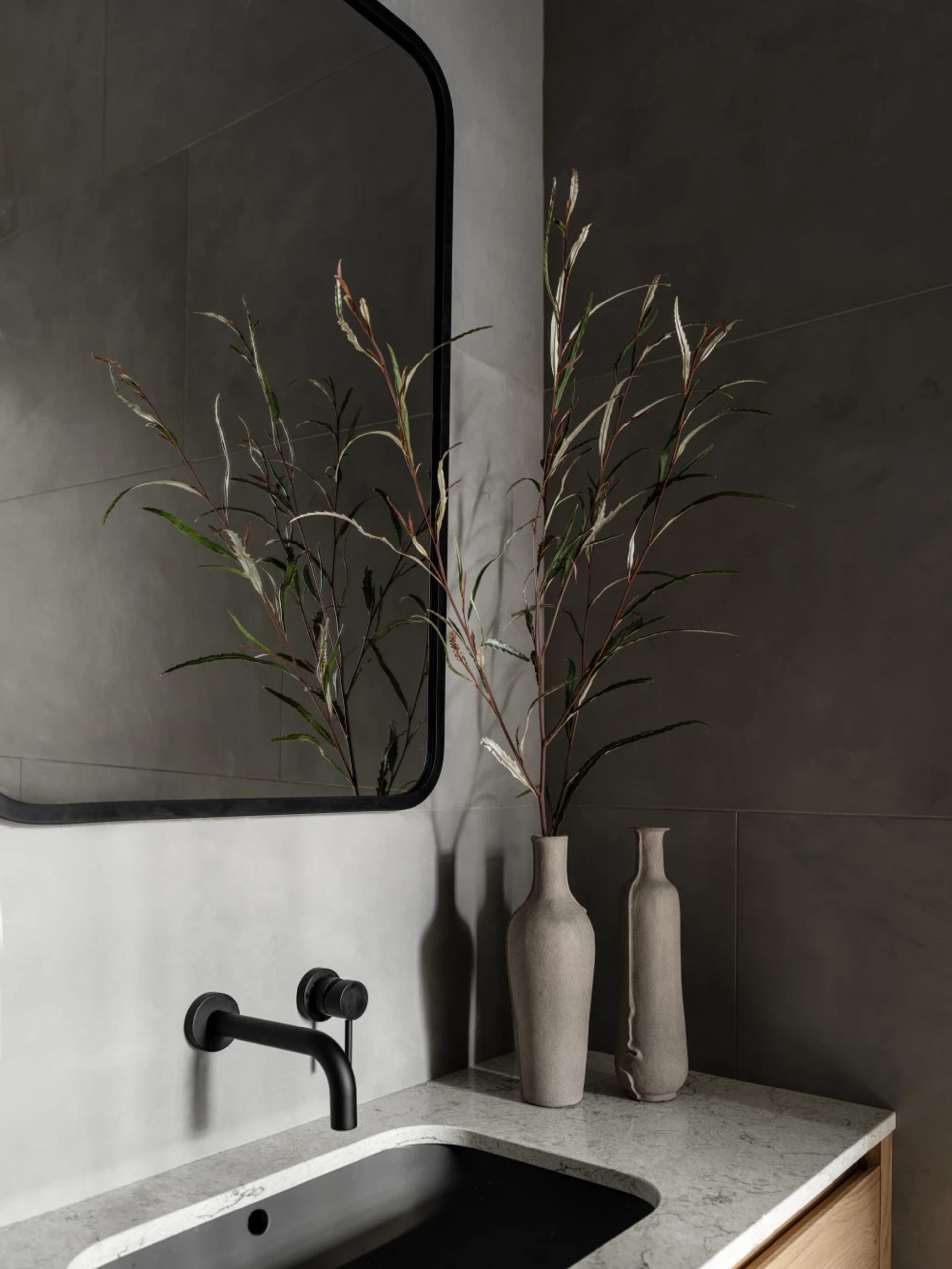 A modern bathroom interior with a black sink, gray marble countertop, and dark gray walls.