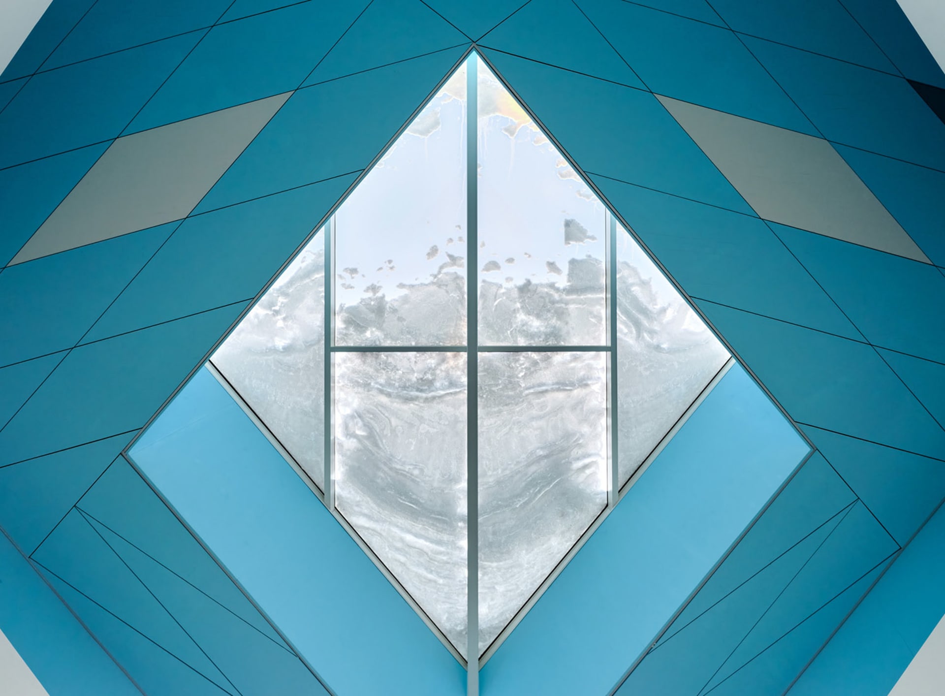 A modern interior design featuring a glass window with a blue geometric pattern.