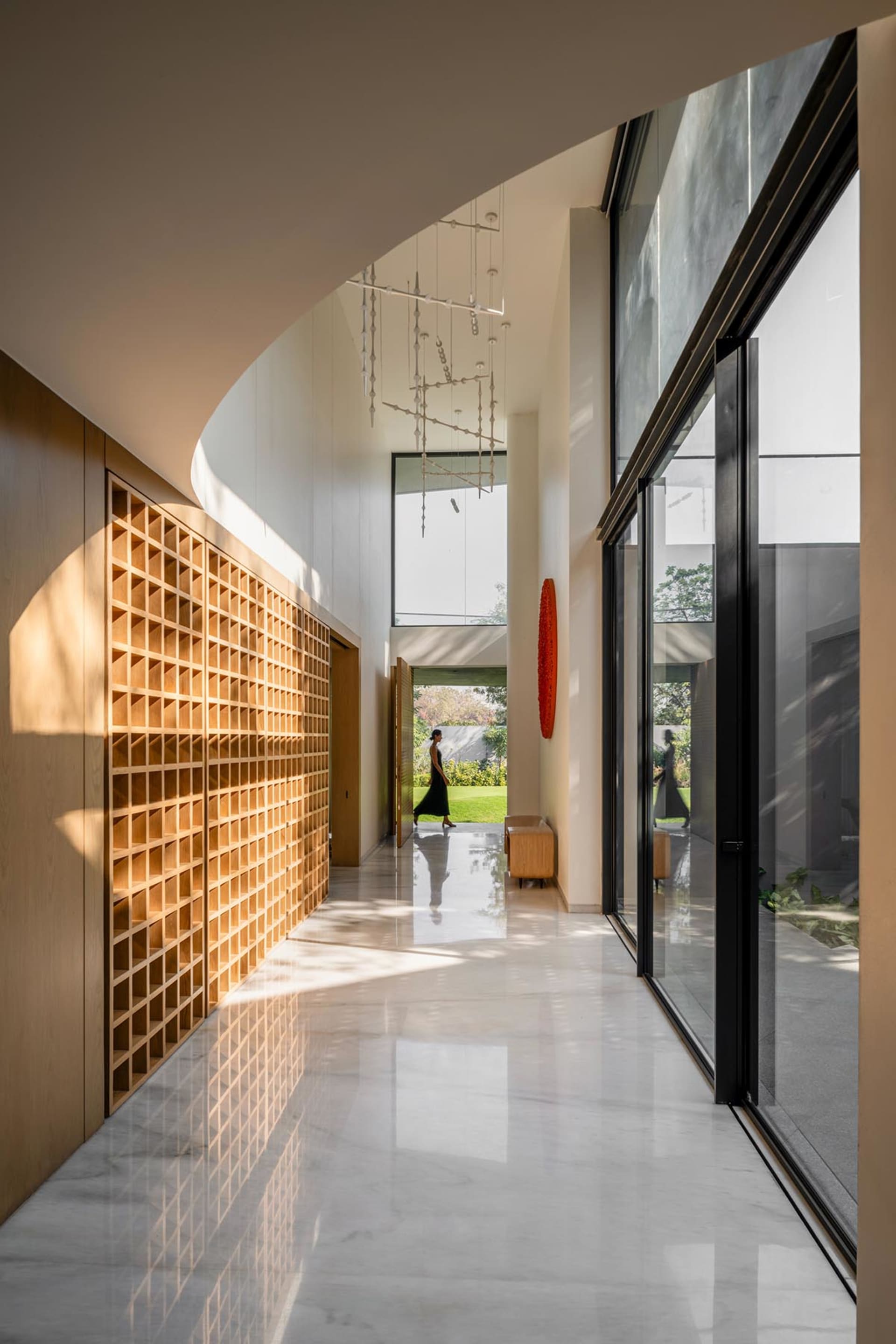 A modern interior hallway featuring marble flooring, wooden accents, and large glass windows.
